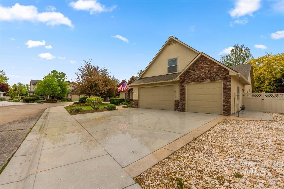 View of property exterior with driveway, stucco siding, stone siding, and roof with shingles