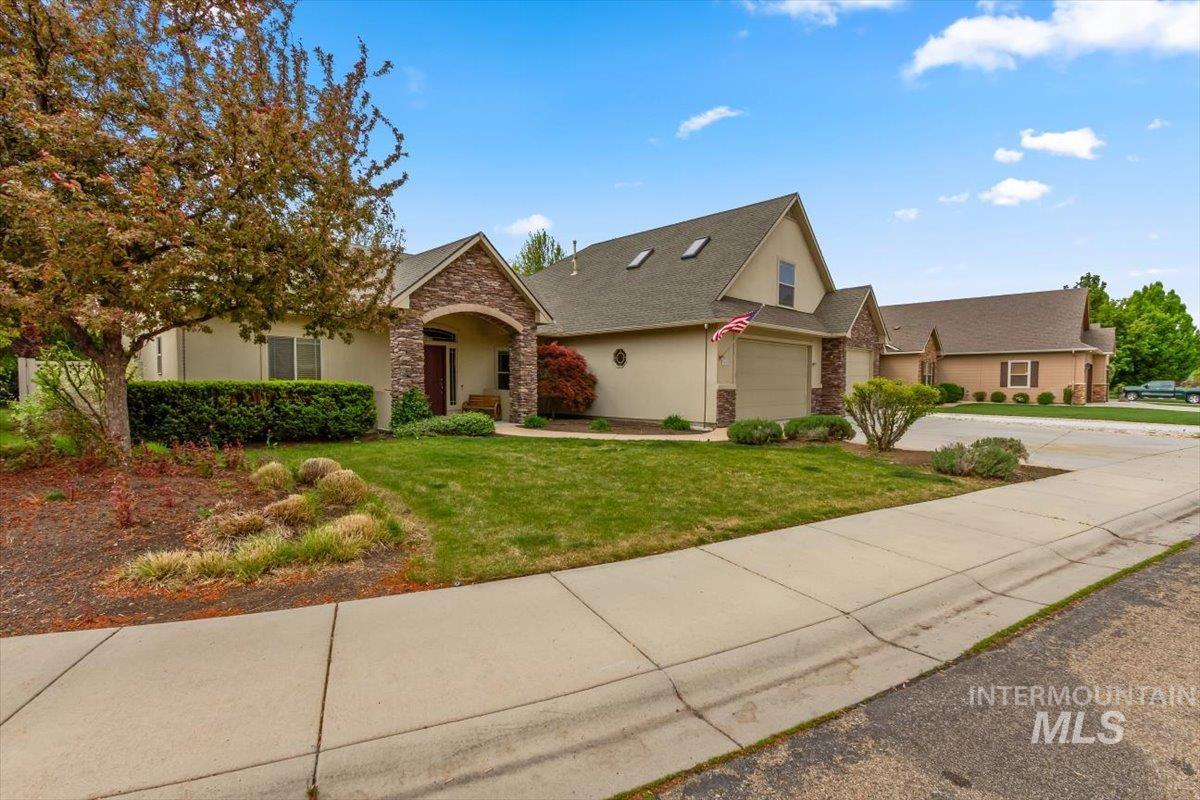 View of front of home featuring a front lawn, stone siding, stucco siding, concrete driveway, and a shingled roof