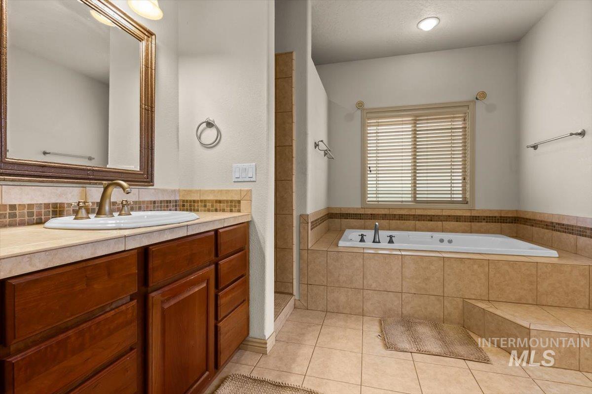 Full bathroom with vanity, a bath, light tile patterned floors, tiled shower, and tasteful backsplash