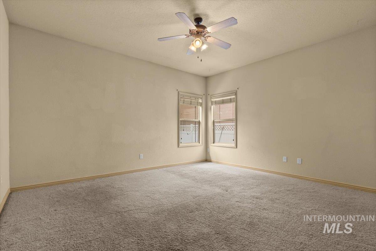 Carpeted empty room featuring a textured ceiling and a ceiling fan