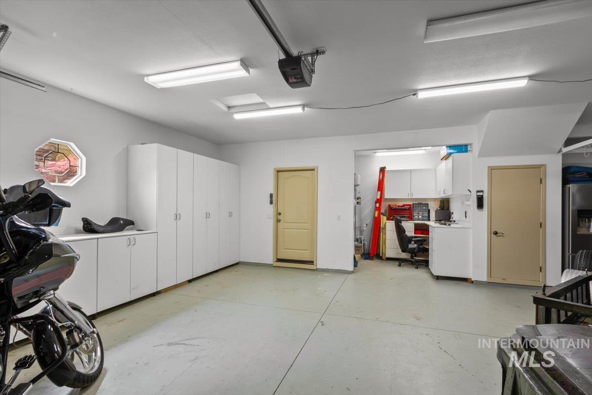 Garage with a garage door opener and stainless steel refrigerator with ice dispenser