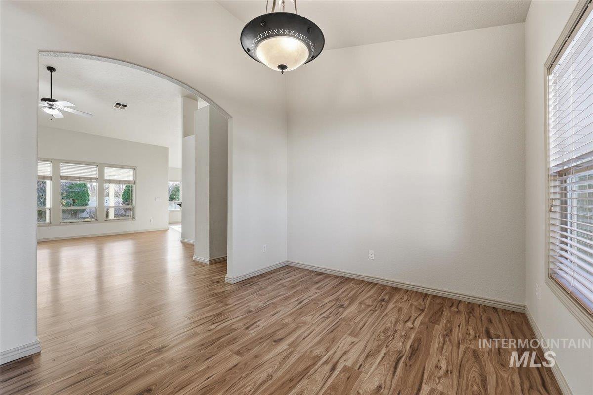 Spare room featuring arched walkways, light wood finished floors, and ceiling fan