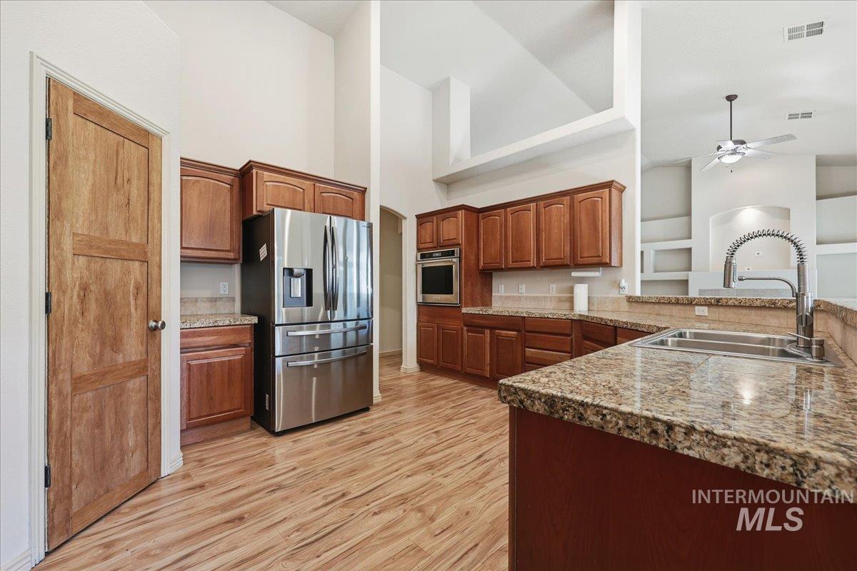 Kitchen featuring appliances with stainless steel finishes, high vaulted ceiling, arched walkways, light wood-style floors, and ceiling fan