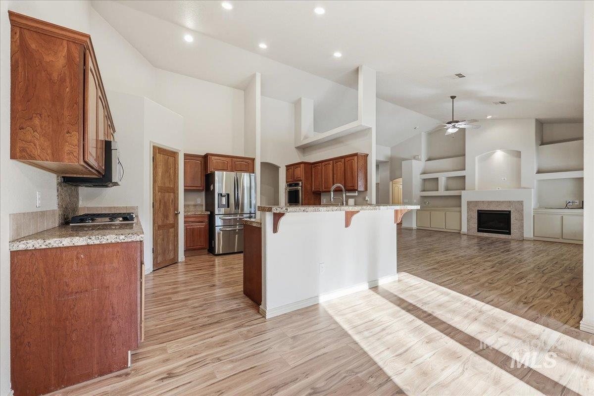 Kitchen featuring a breakfast bar, built in features, a fireplace, light wood-type flooring, and stainless steel appliances