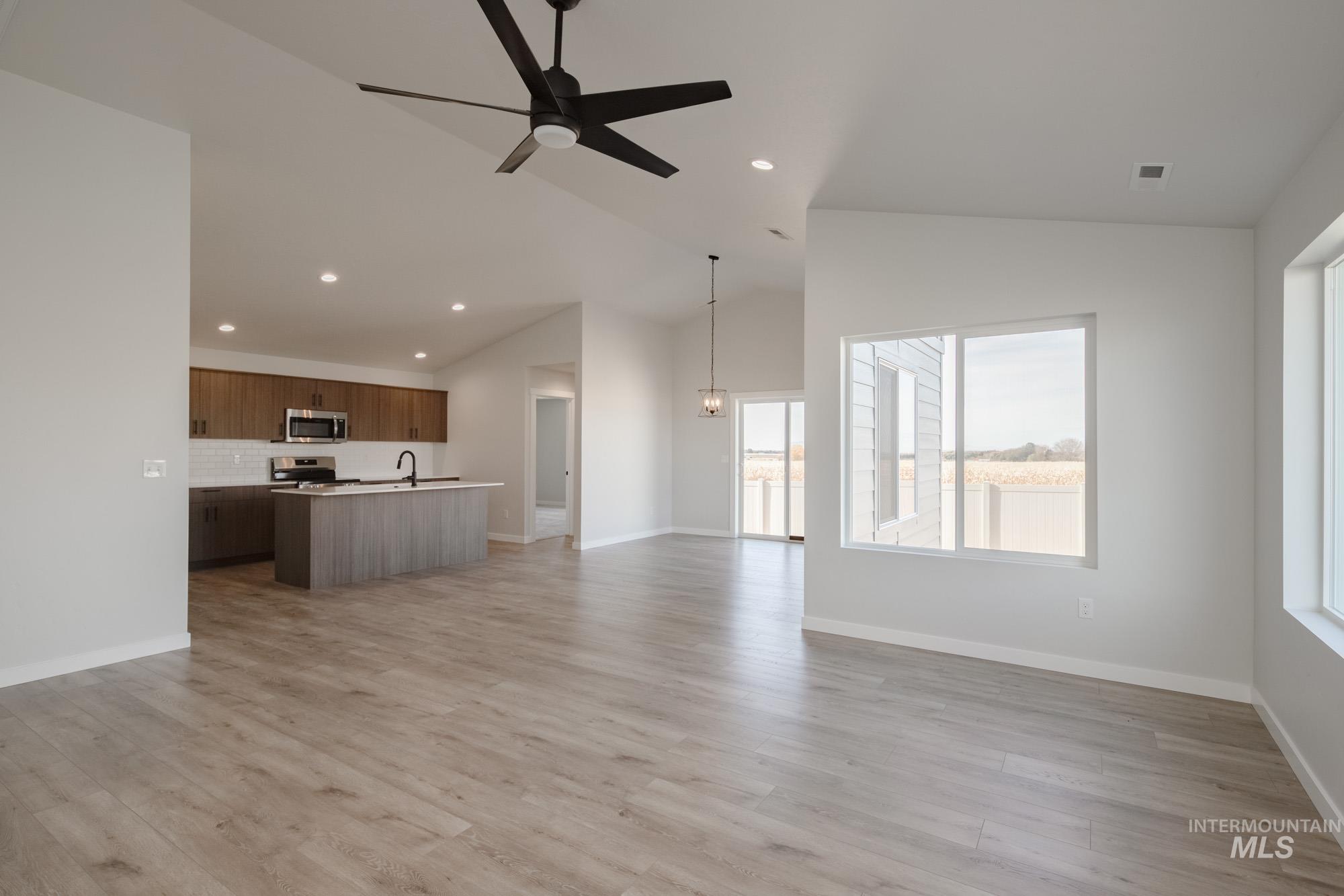 Unfurnished living room with ceiling fan, light wood-type flooring, recessed lighting, and high vaulted ceiling