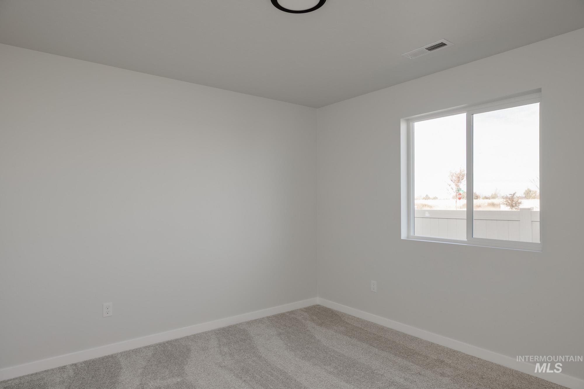 Carpeted spare room featuring baseboards