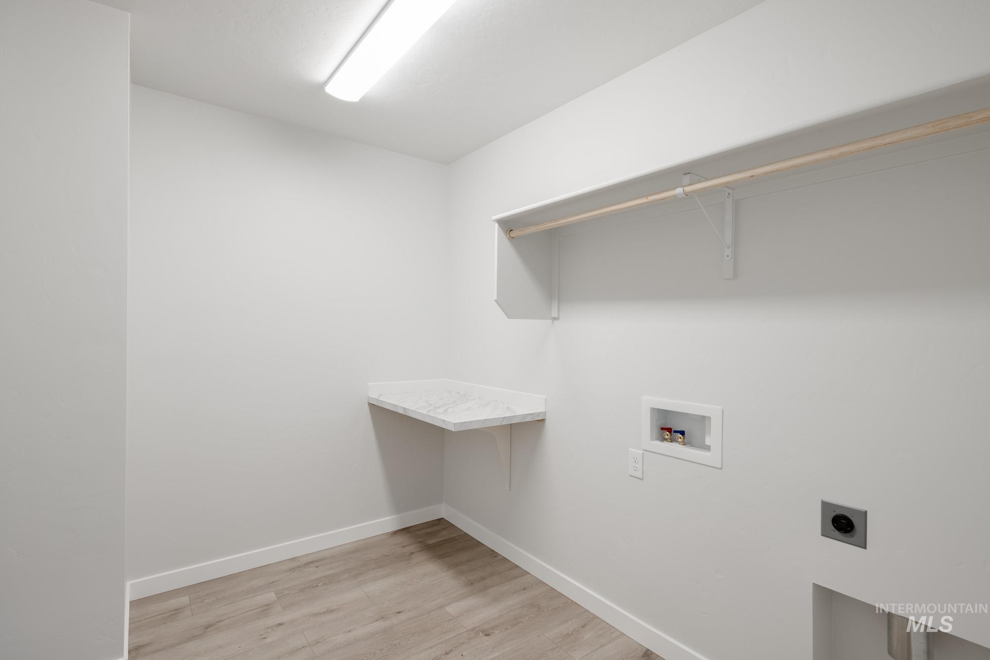 Laundry room with hookup for a washing machine, light wood-style floors, and electric dryer hookup