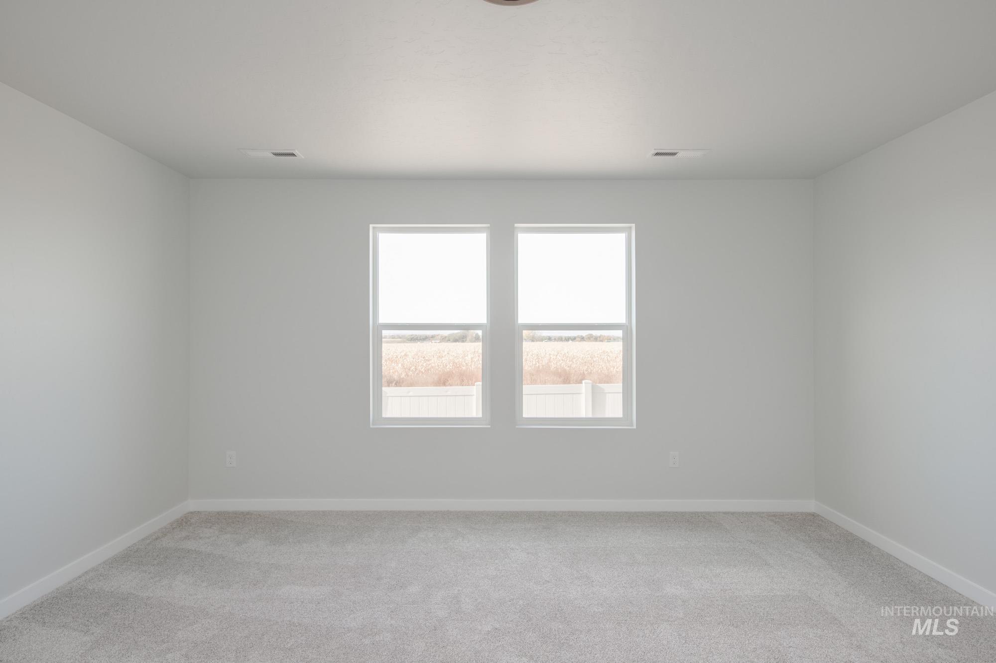 Empty room featuring light colored carpet and baseboards