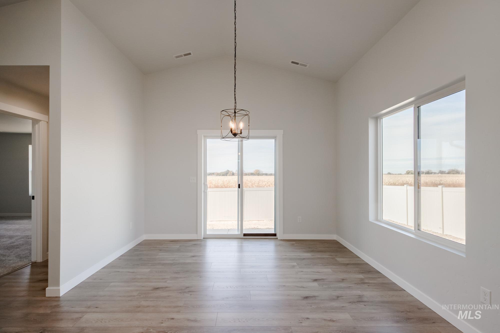 Unfurnished dining area featuring lofted ceiling, light wood-style floors, and a chandelier