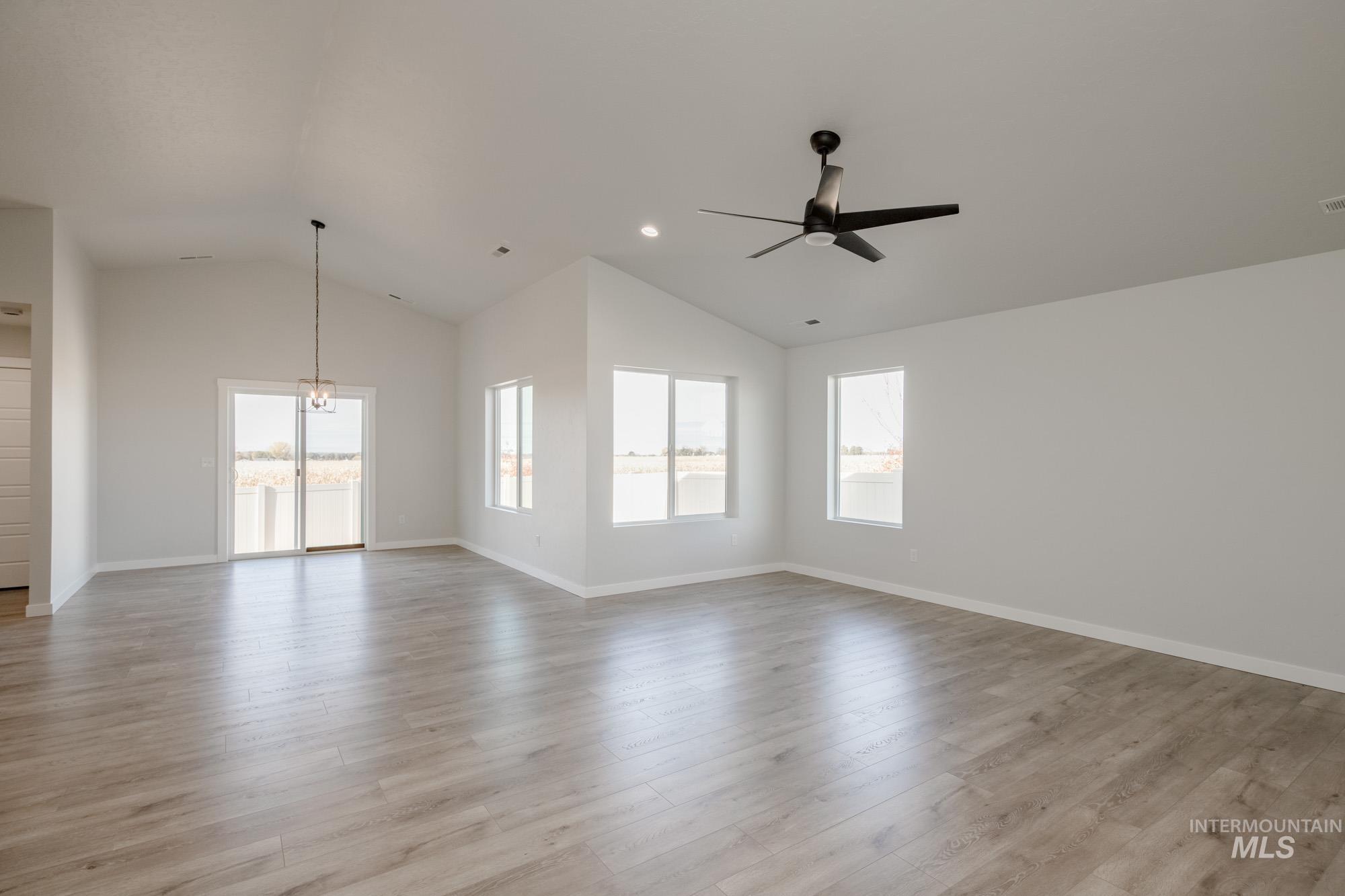 Empty room with lofted ceiling, light wood finished floors, ceiling fan, and recessed lighting