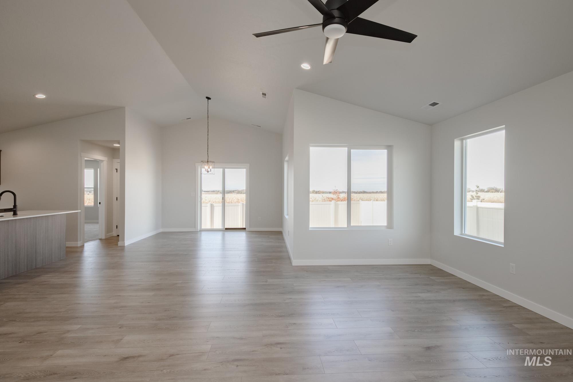 Unfurnished living room featuring lofted ceiling, light wood-style flooring, recessed lighting, a chandelier, and ceiling fan