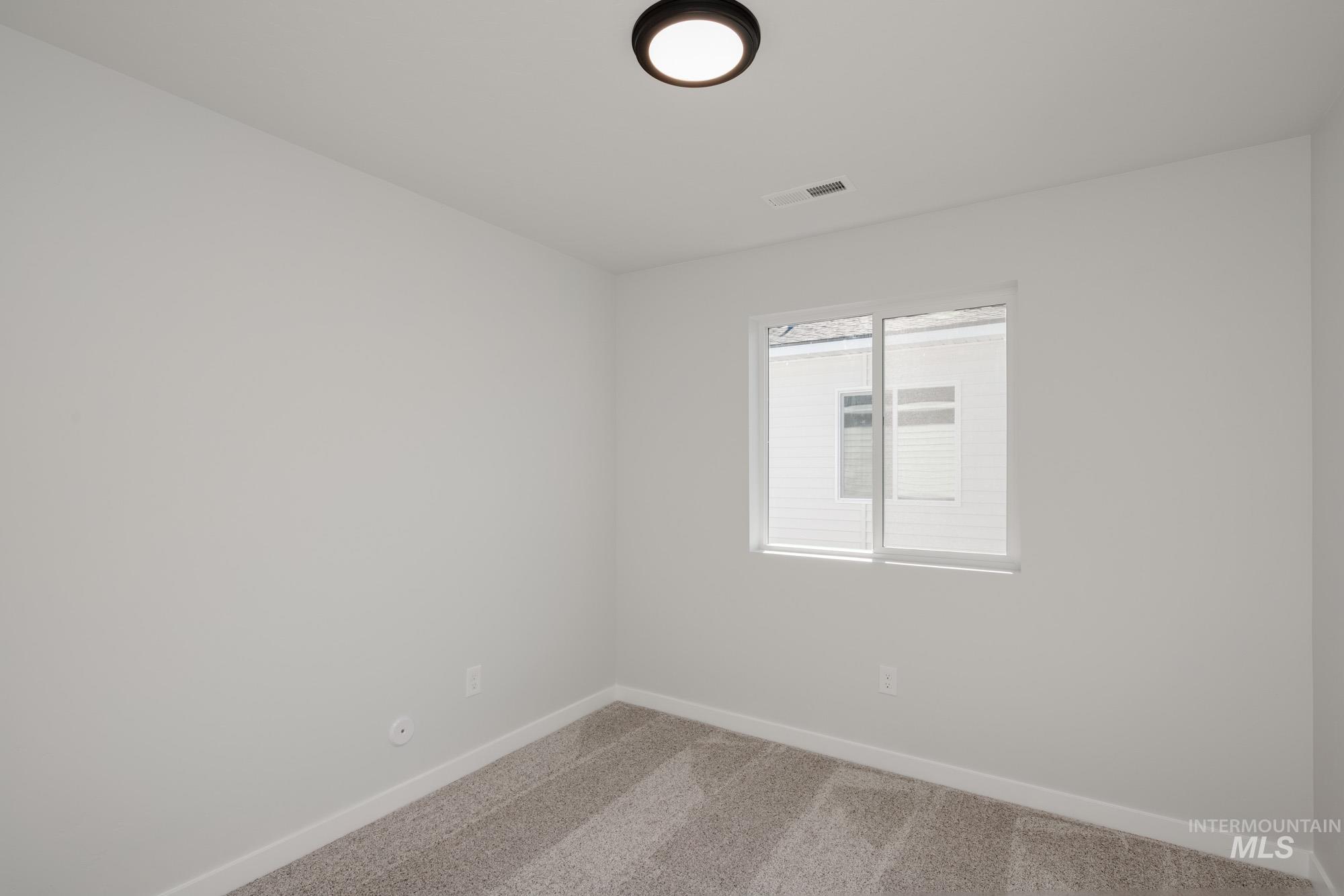 Carpeted spare room featuring baseboards
