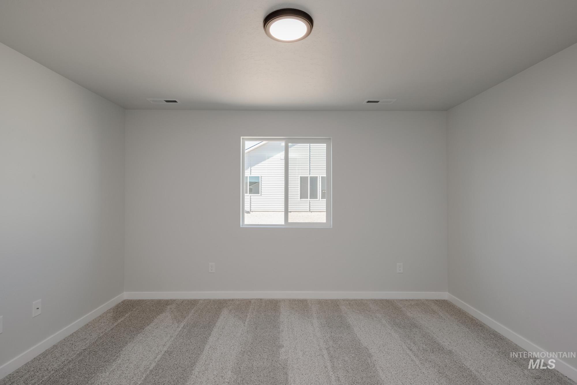 Spare room featuring light colored carpet and baseboards