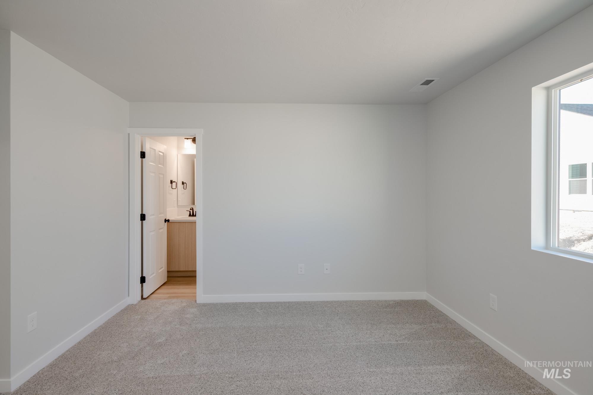 Spare room featuring light carpet and baseboards