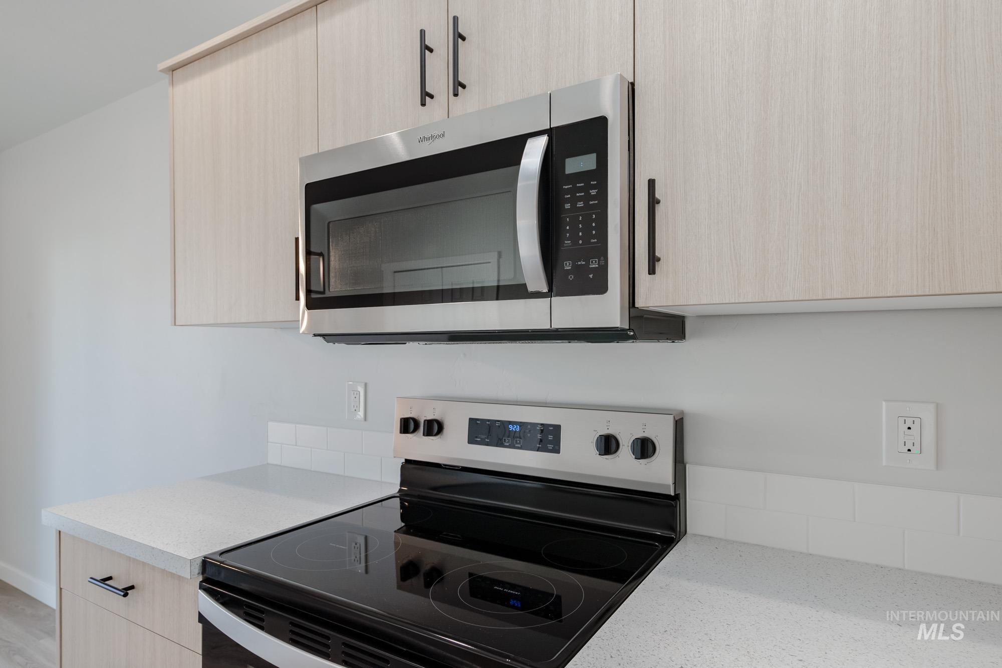Kitchen with light brown cabinetry, stainless steel appliances, modern cabinets, and light stone countertops