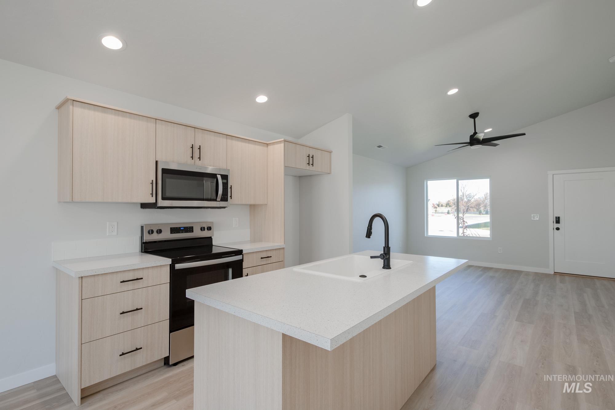 Kitchen featuring light brown cabinetry, stainless steel appliances, light wood-style flooring, light countertops, and recessed lighting