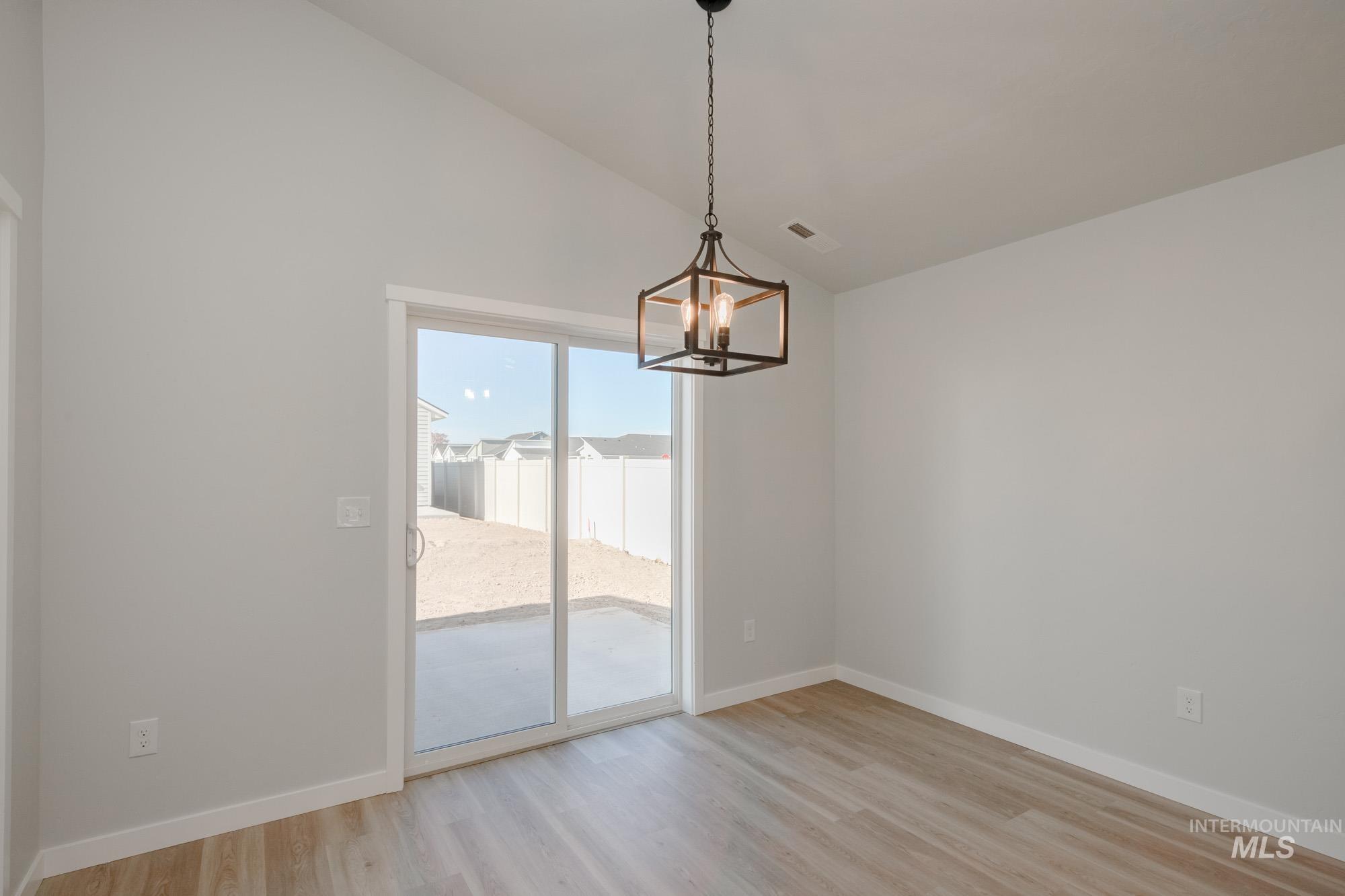 Unfurnished dining area with lofted ceiling, light wood-type flooring, and a chandelier