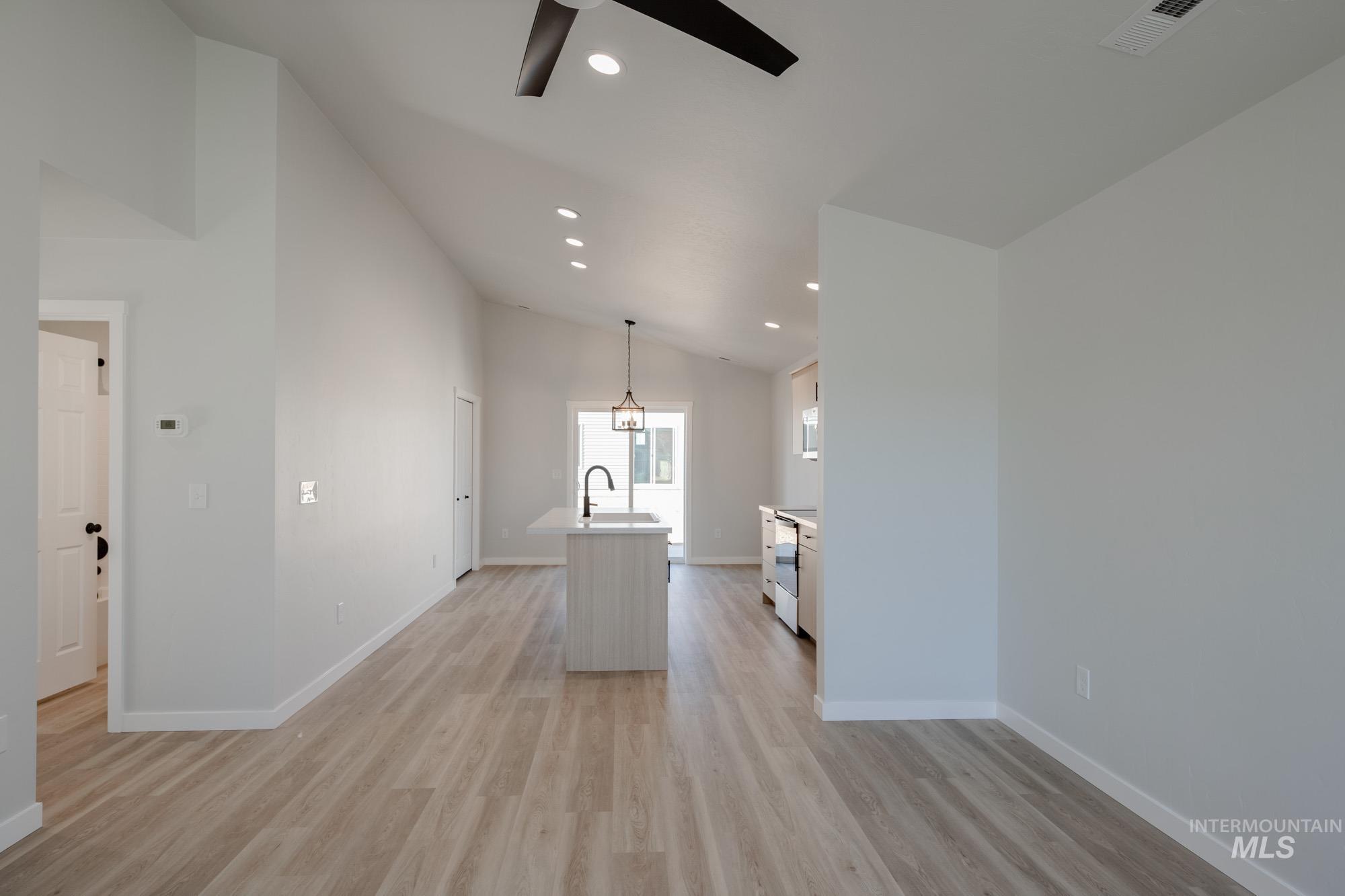 Empty room featuring lofted ceiling, recessed lighting, light wood finished floors, and ceiling fan