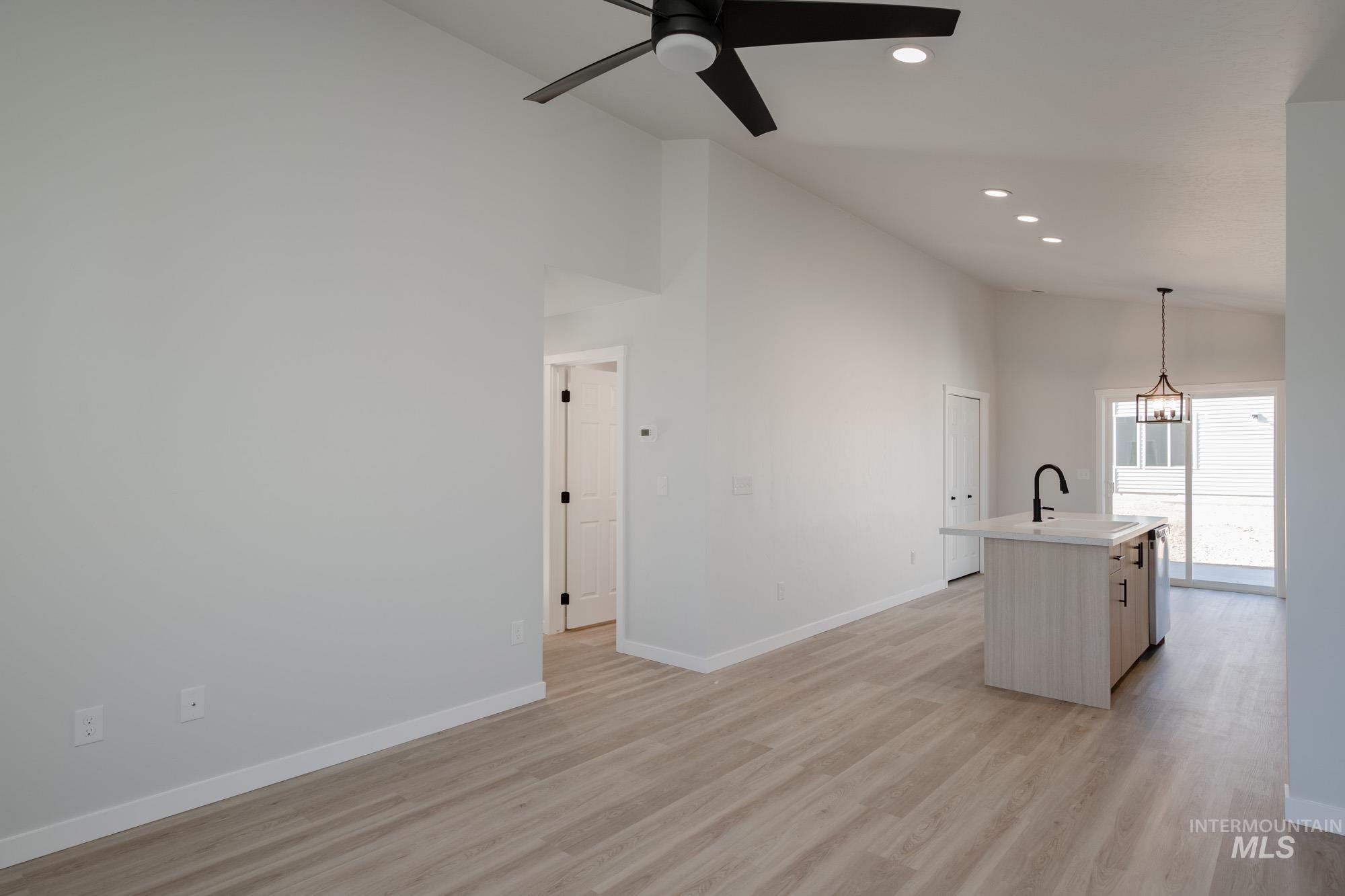 Kitchen featuring high vaulted ceiling, a kitchen island with sink, decorative light fixtures, light wood-style floors, and recessed lighting