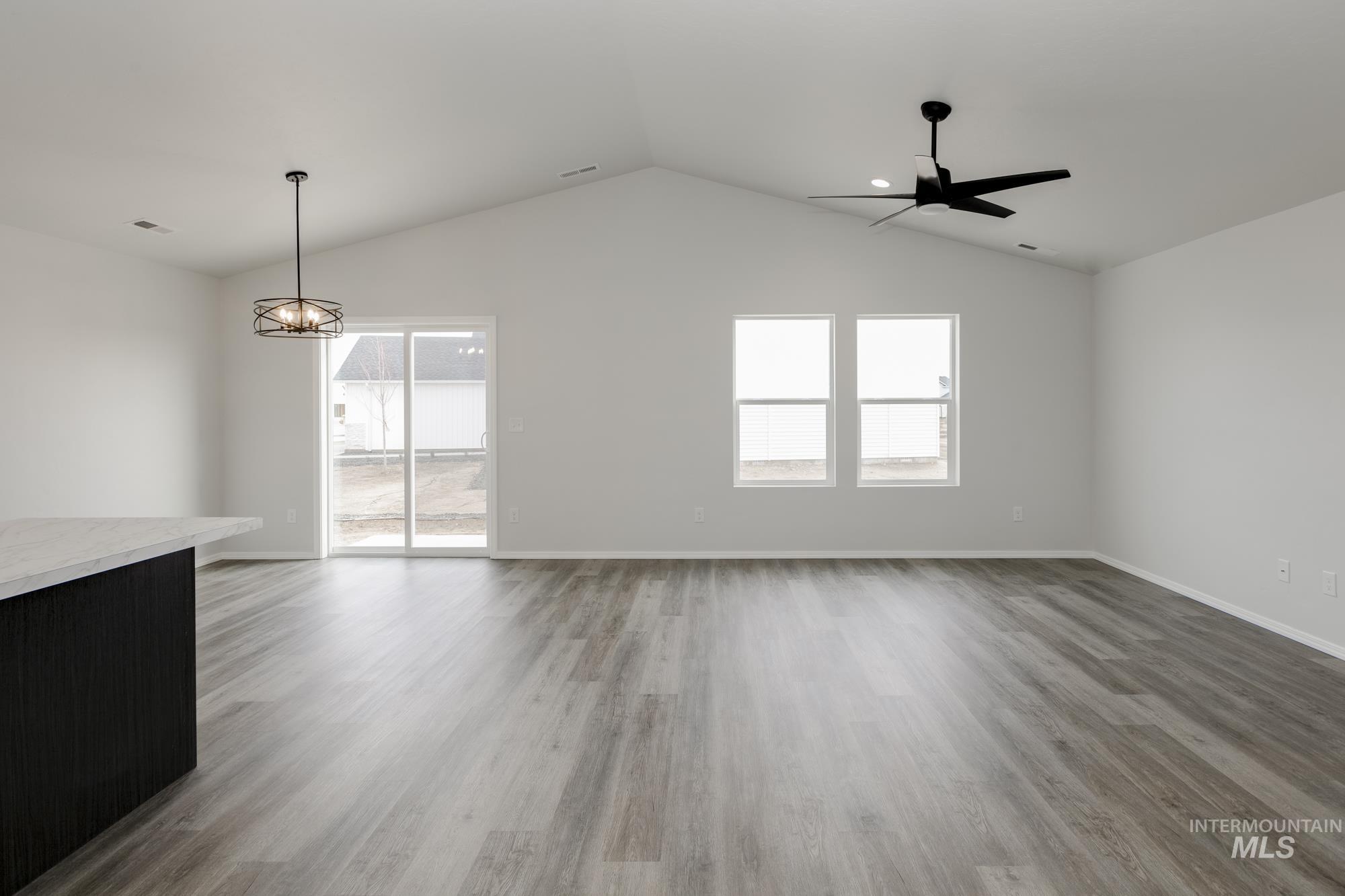 Empty room featuring light wood-style flooring, lofted ceiling, and a chandelier