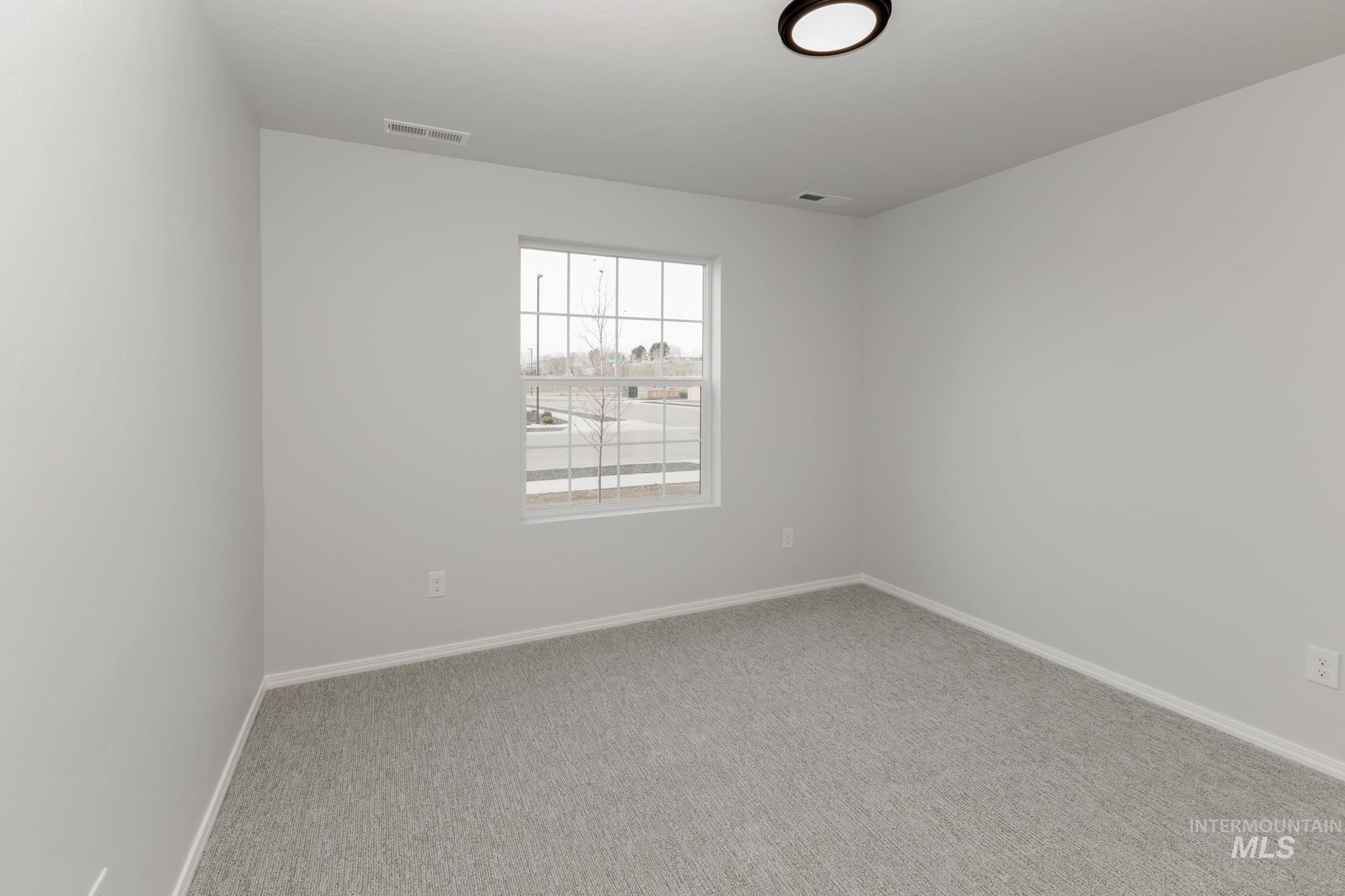 Spare room featuring light colored carpet and baseboards