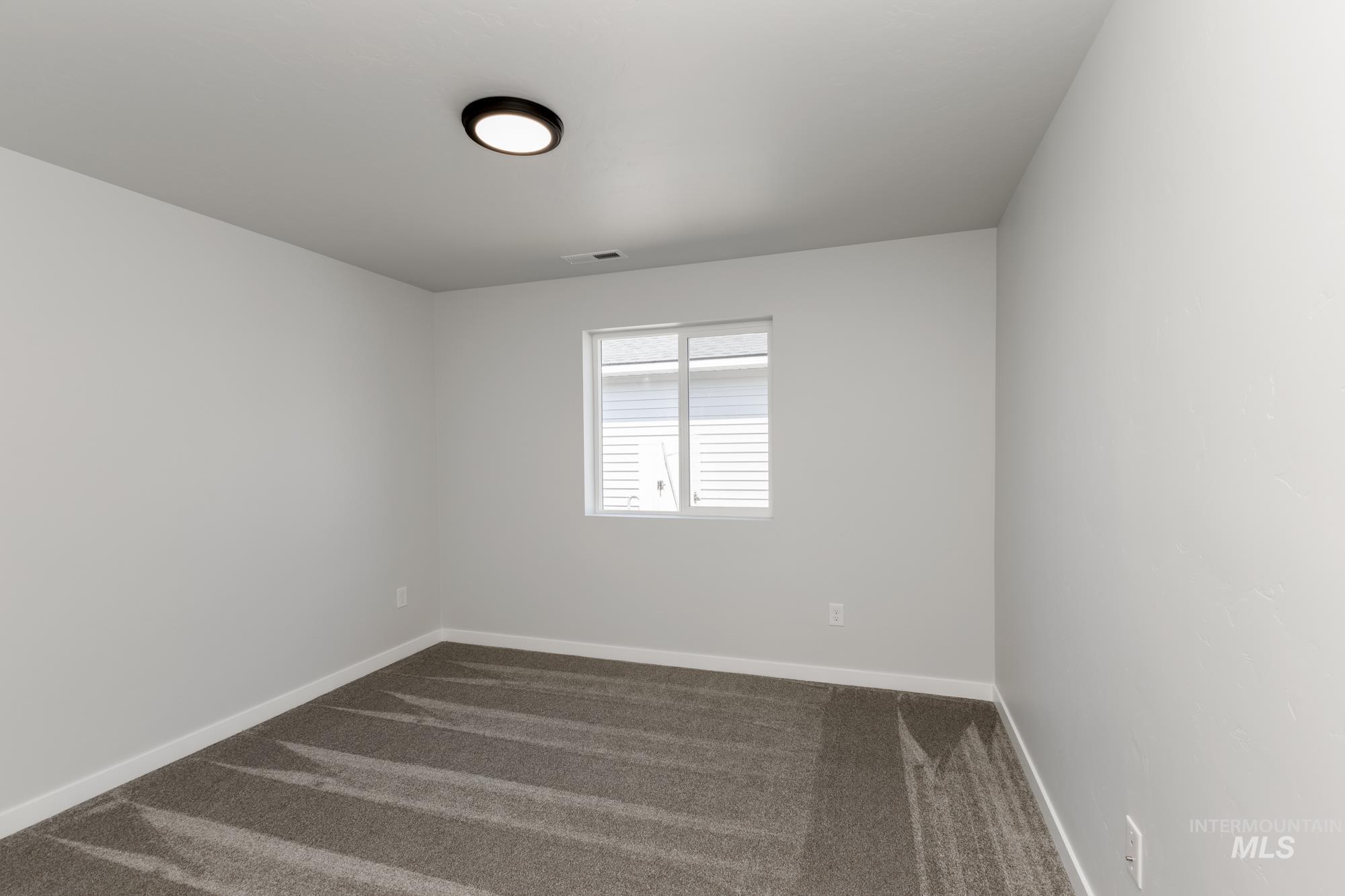 Empty room featuring dark carpet and baseboards