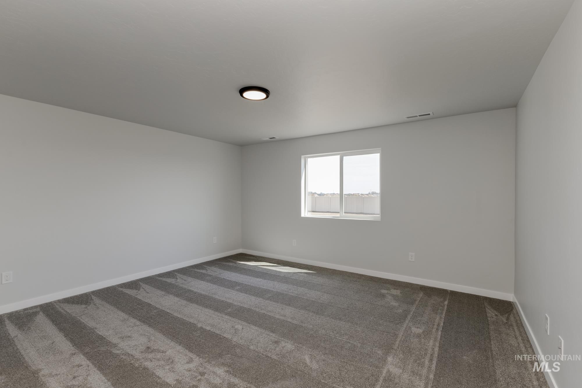 Carpeted spare room with baseboards