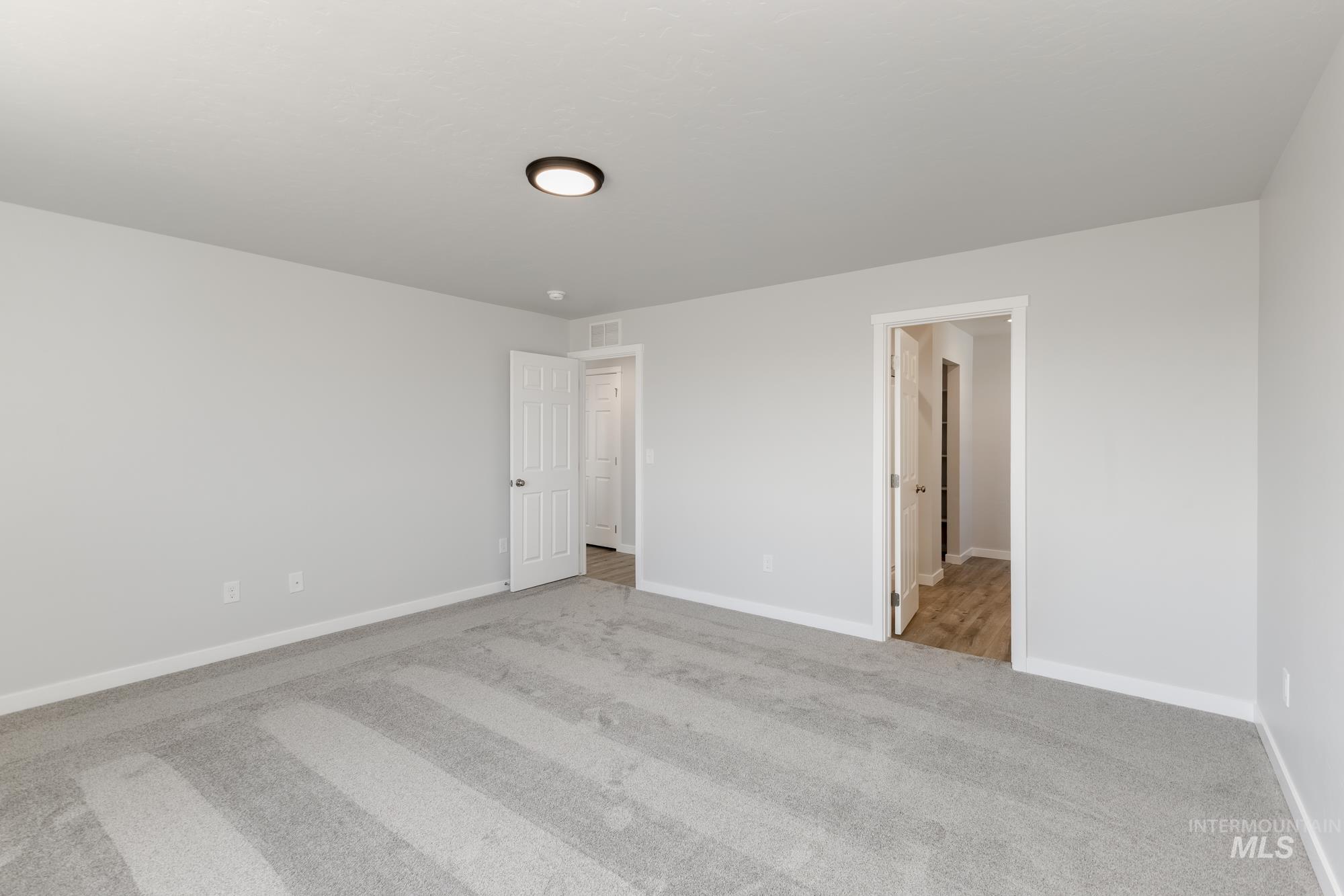 Unfurnished bedroom featuring light carpet and baseboards