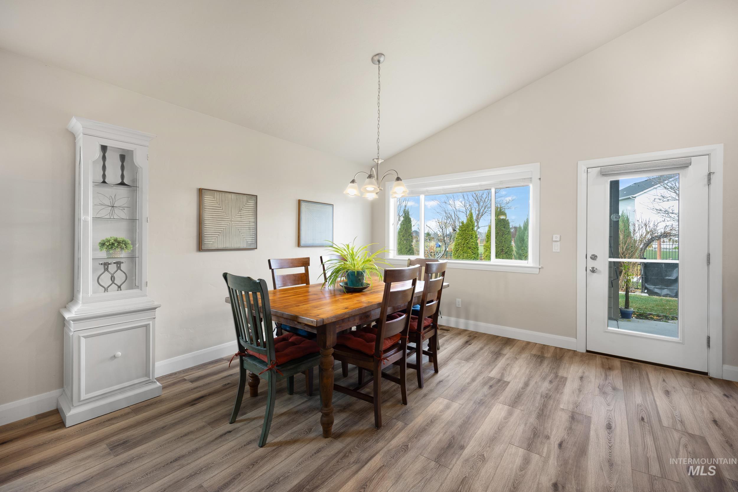 Dining space with vaulted ceiling, light wood-style flooring, and a chandelier