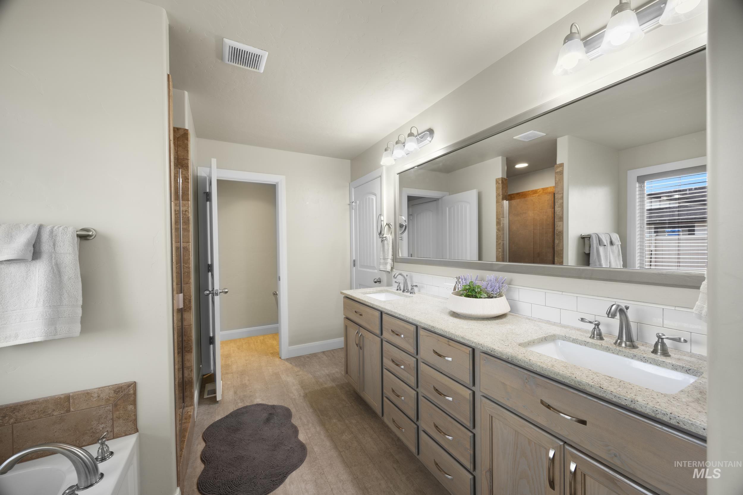 Full bathroom with double vanity, a shower stall, a bath.