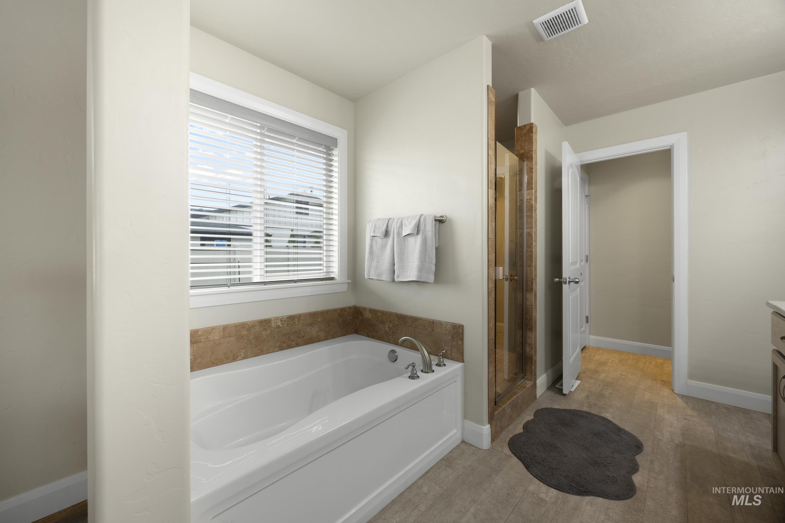 Bathroom featuring a garden tub, vanity, a shower stall