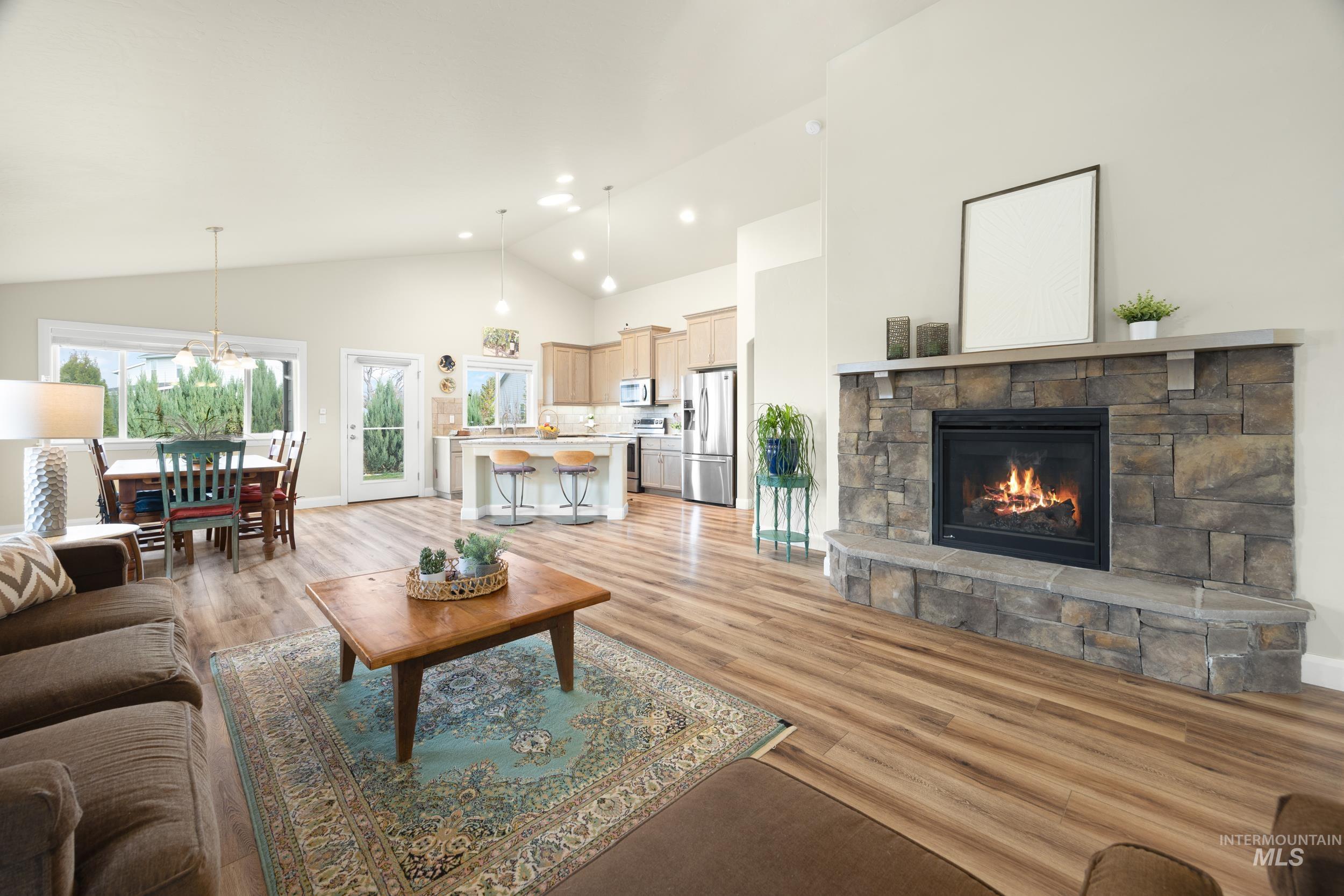 Great Room with a fireplace, high vaulted ceiling, and light wood finished floors