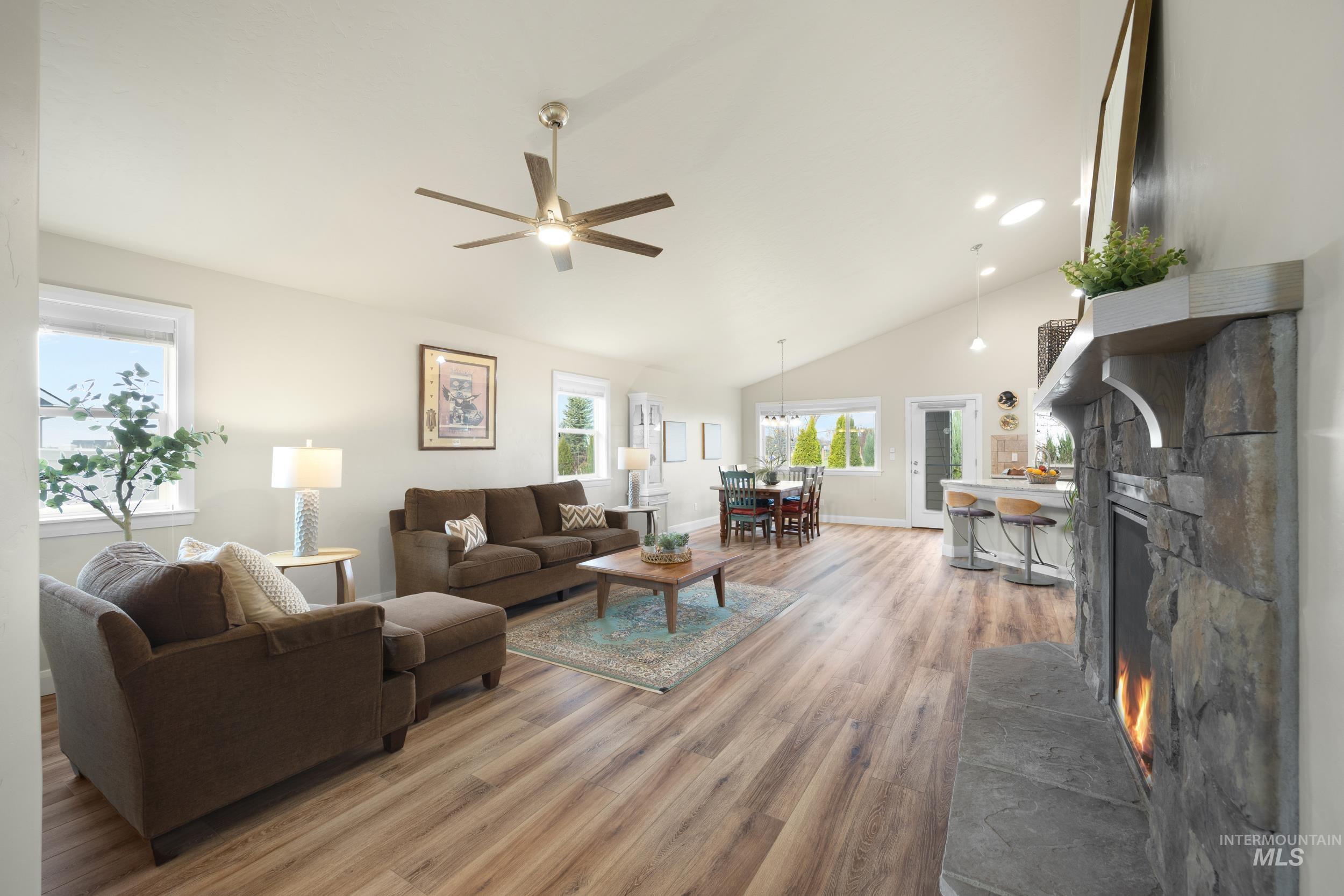 Great Room with a fireplace, lofted ceiling, light wood-style flooring, a ceiling fan, and recessed lighting