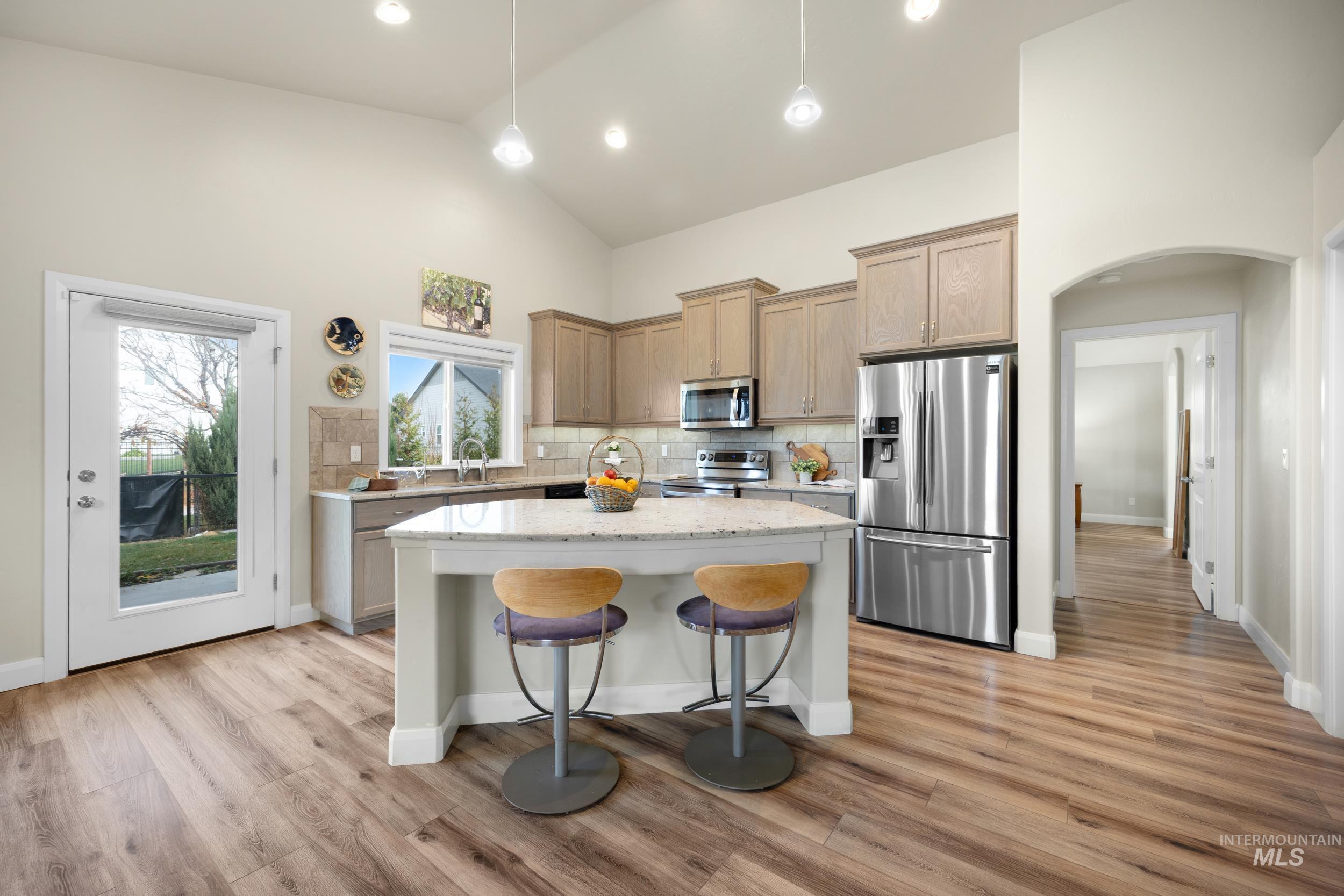 Kitchen with a breakfast bar, appliances with stainless steel finishes, arched walkways, a kitchen island, and pendant lighting