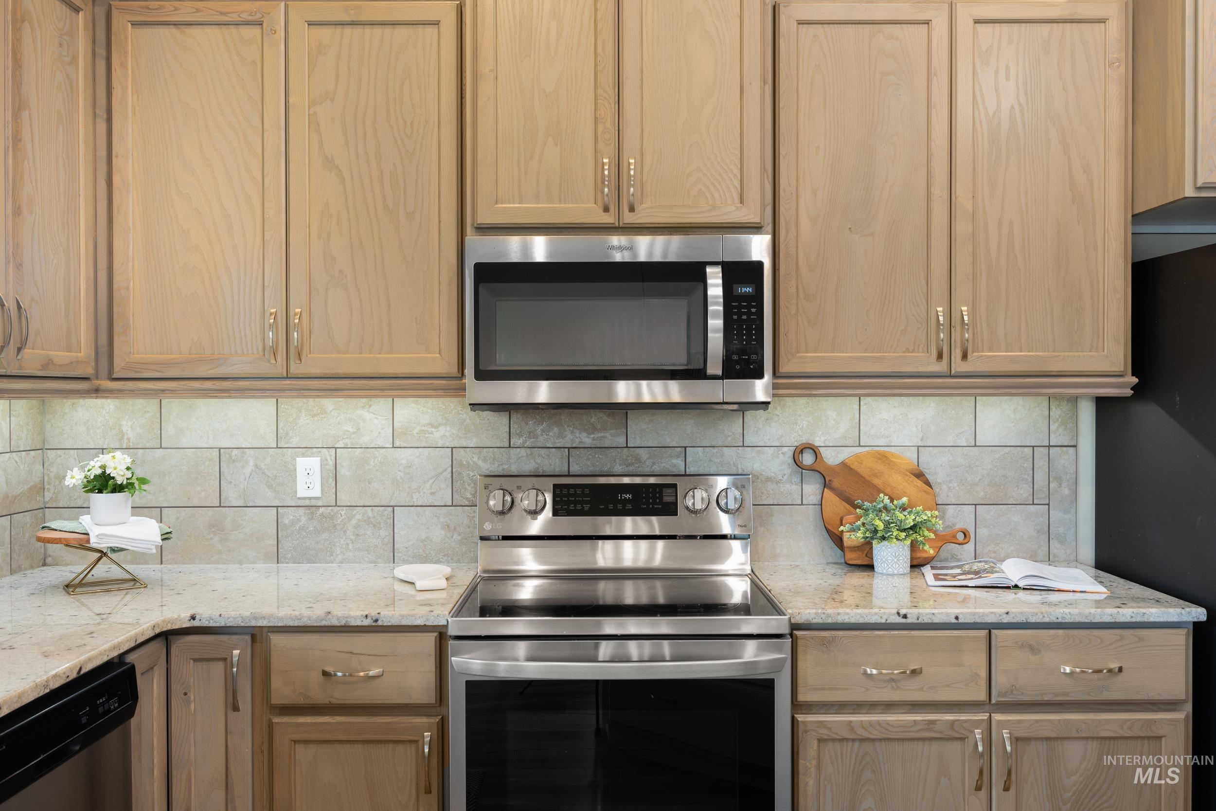 Kitchen with stainless steel appliances, light stone counters, and backsplash
