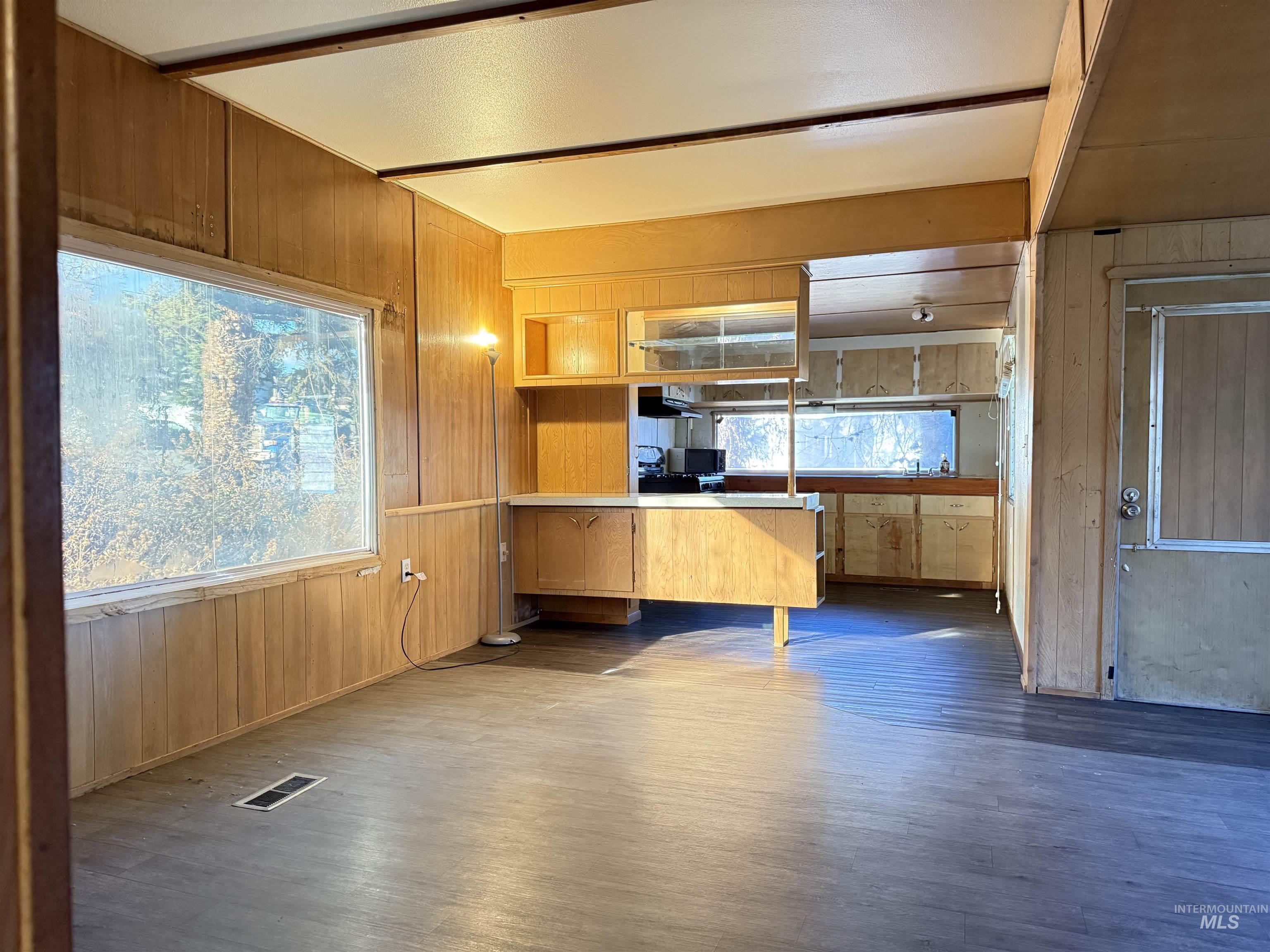 Kitchen featuring wood walls, light countertops, dark wood-type flooring, a peninsula, and open shelves