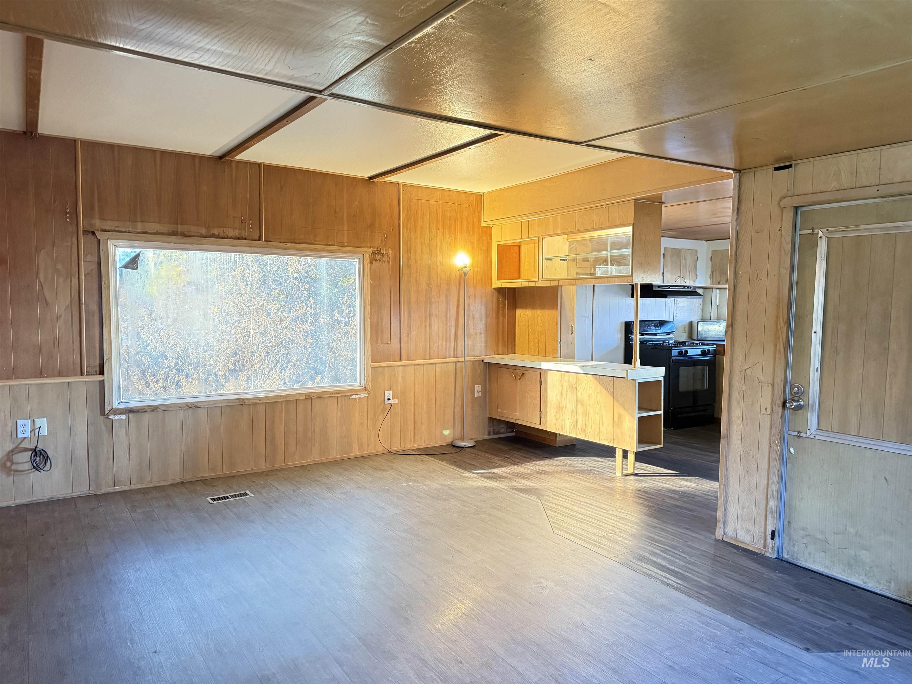 Unfurnished living room with wooden walls and wood finished floors