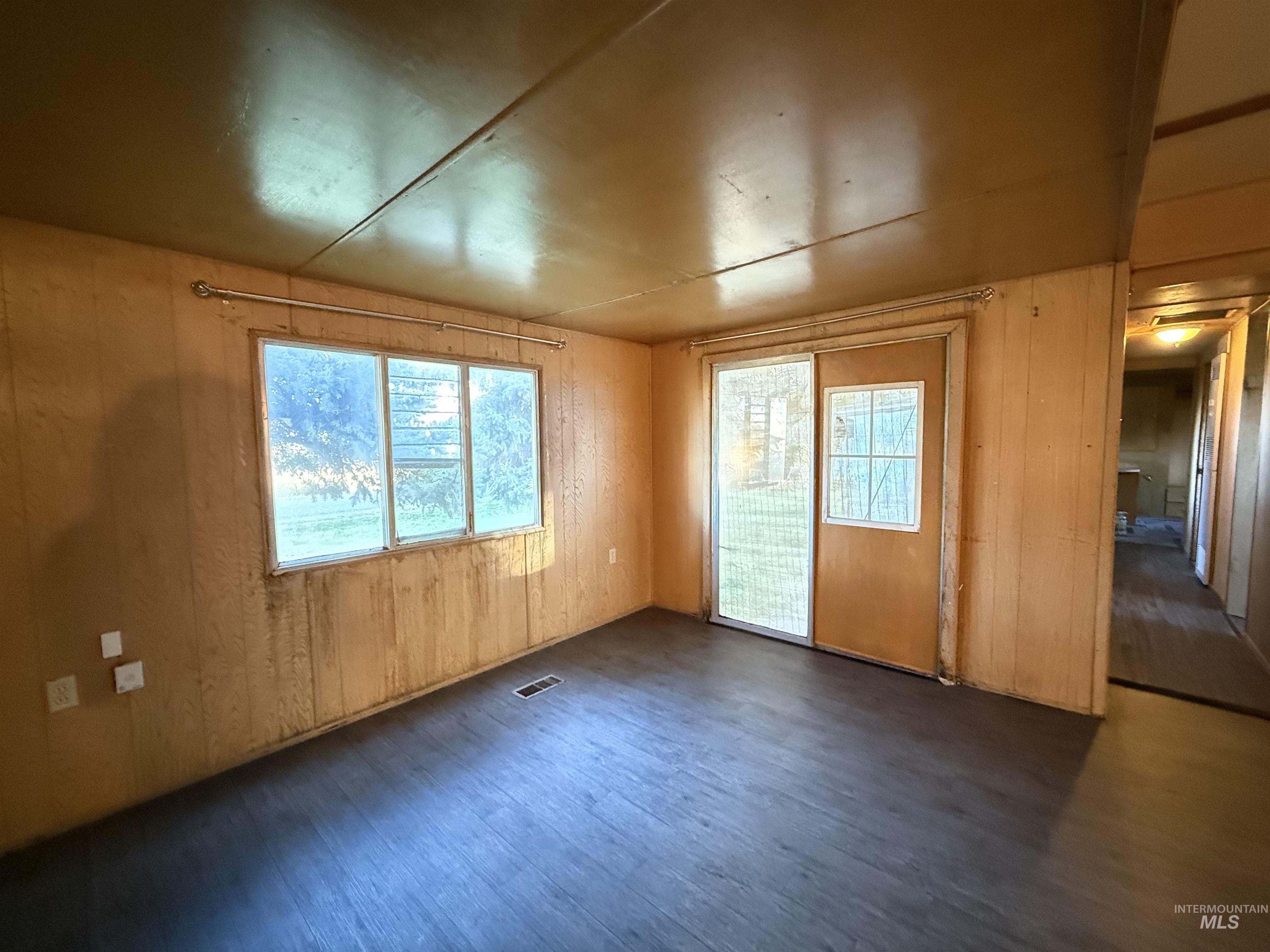 Unfurnished room with wood walls and dark wood finished floors