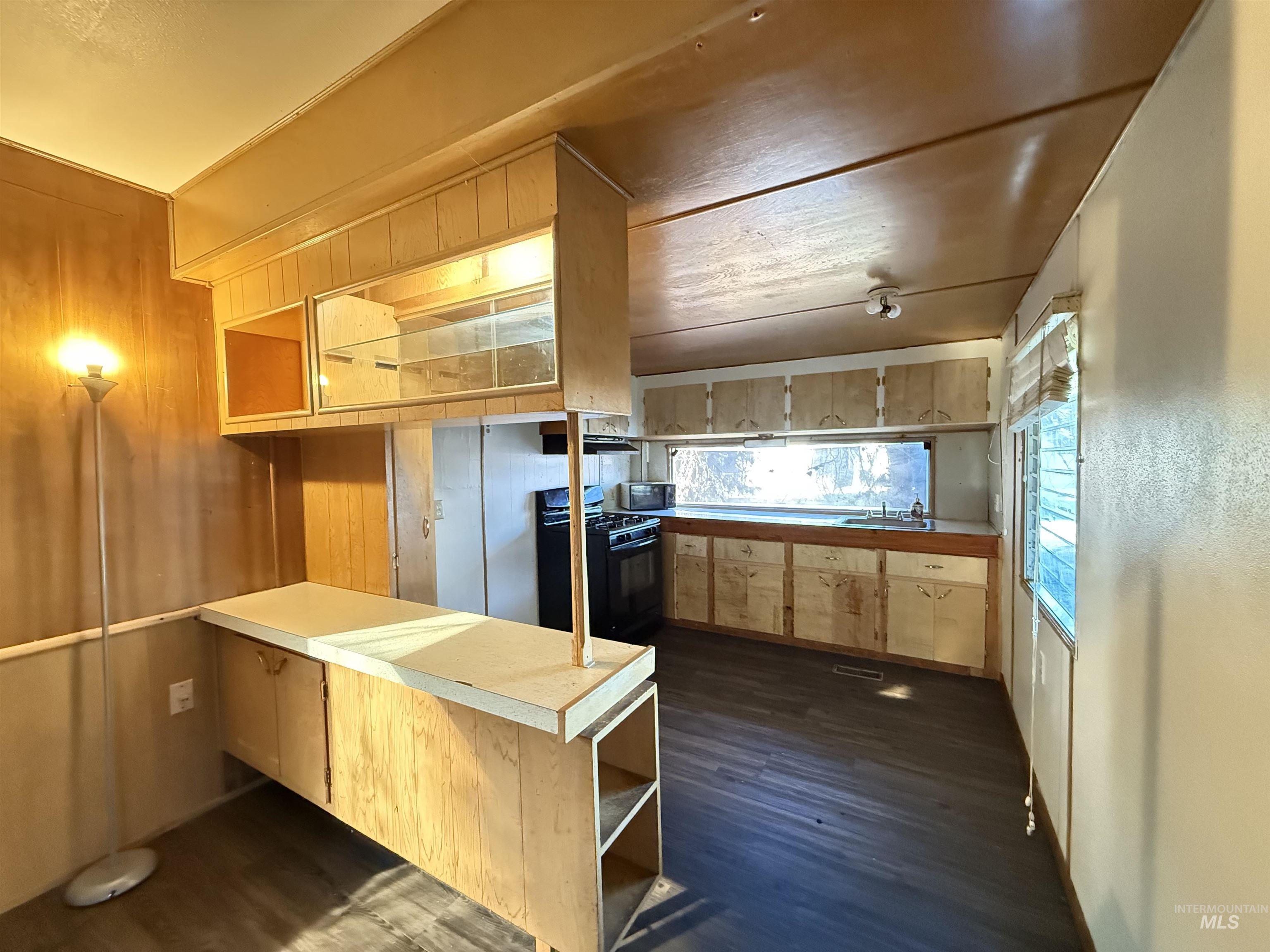 Kitchen with open shelves, black gas range oven, dark wood-style floors, and light countertops
