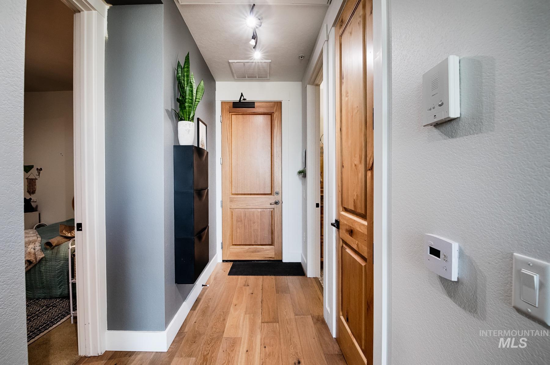 Hallway featuring light wood-style flooring and a textured wall