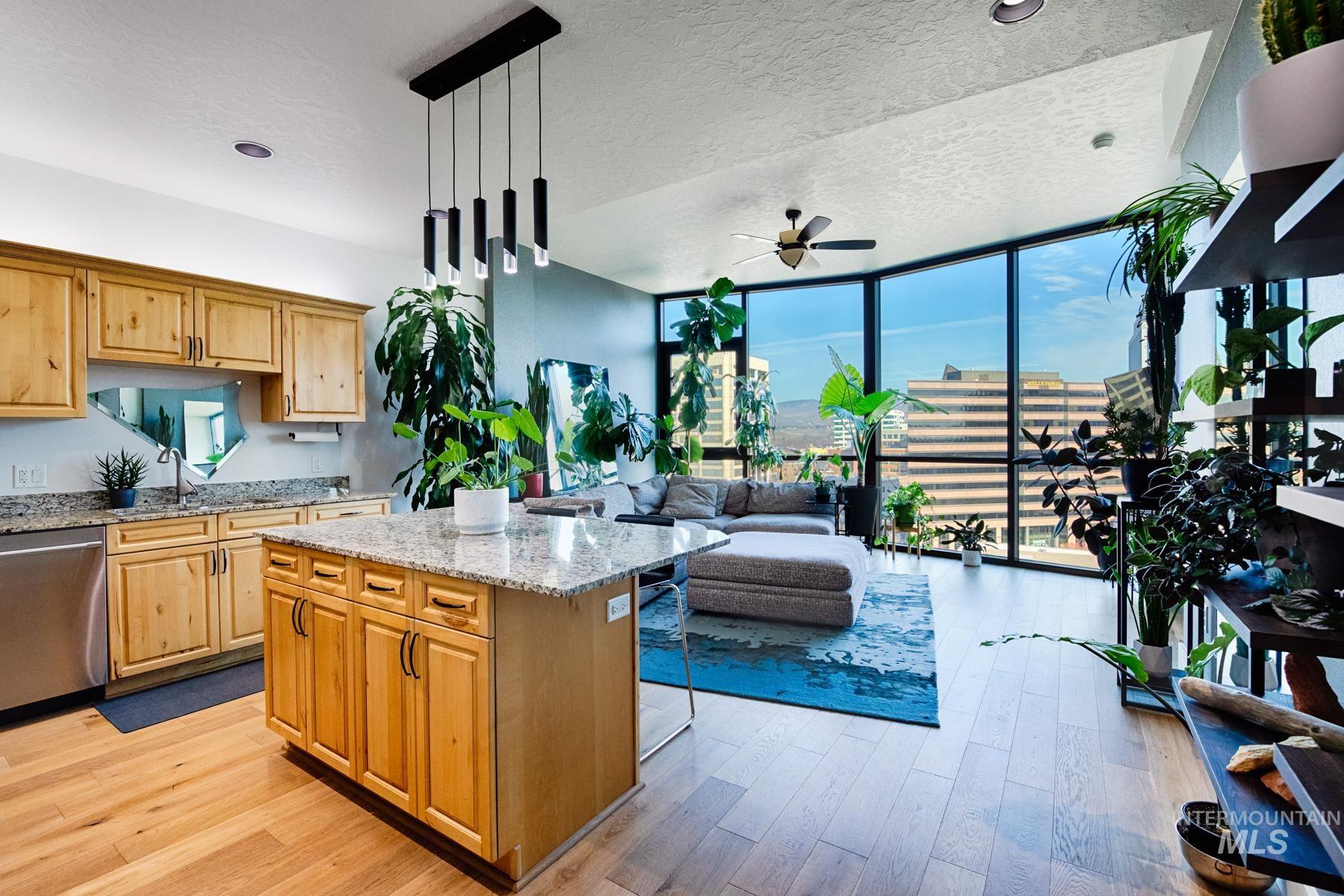 Kitchen featuring expansive windows, light stone countertops, a textured ceiling, dishwasher, and light wood-style flooring