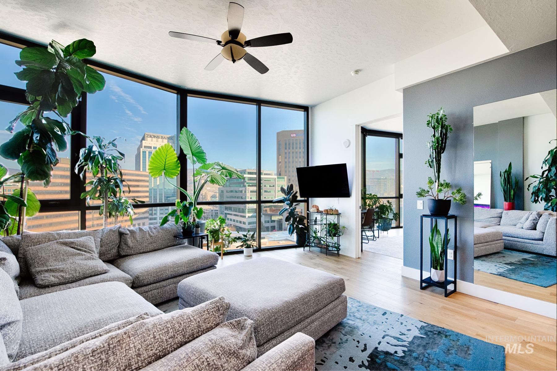 Living area with wood finished floors, a textured ceiling, expansive windows, and a ceiling fan