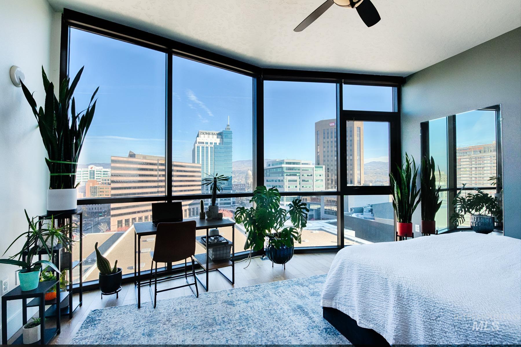 Bedroom featuring floor to ceiling windows, a city view, wood finished floors, and a ceiling fan