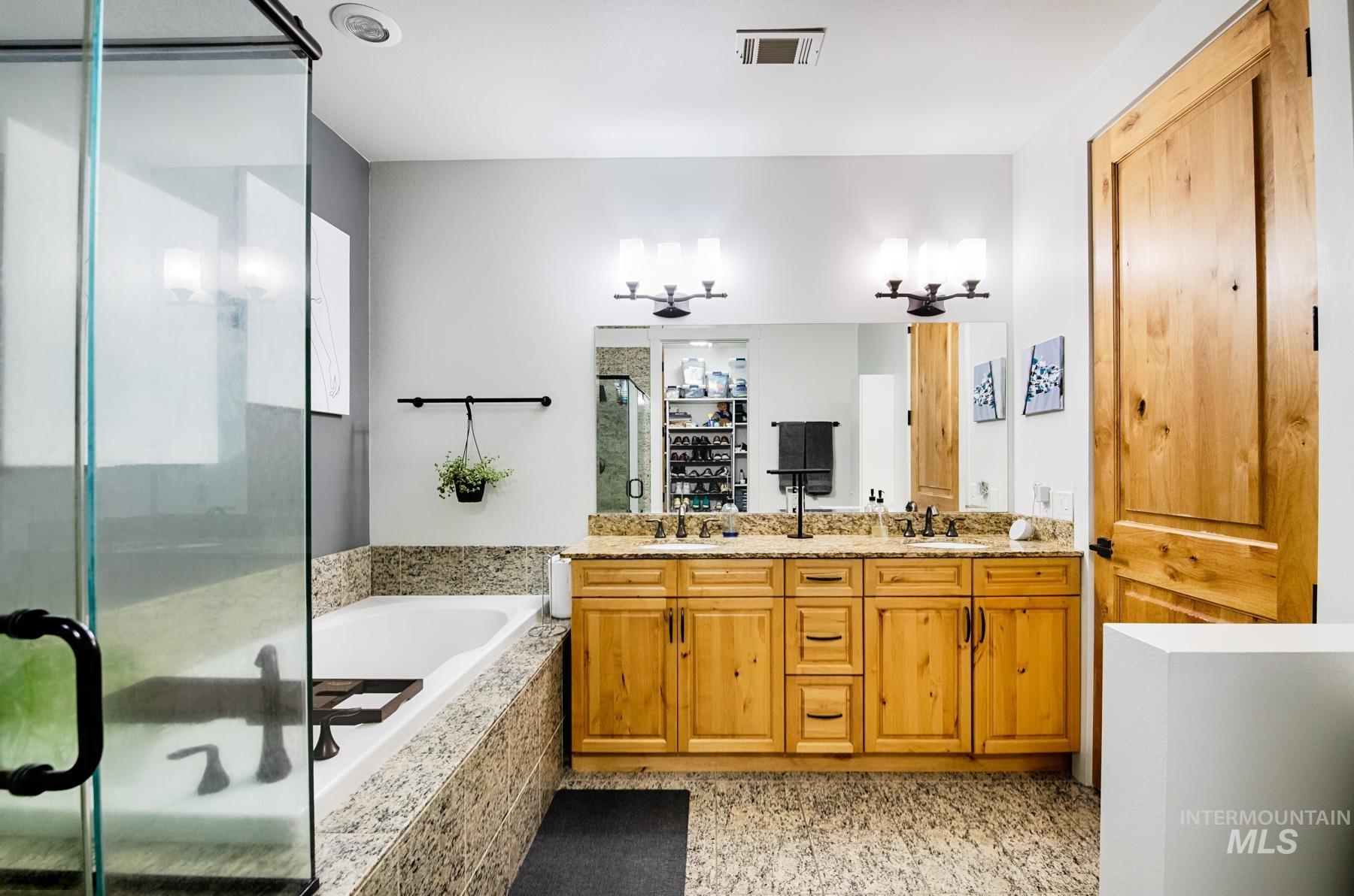 Full bathroom featuring a bath, double vanity, and a shower stall