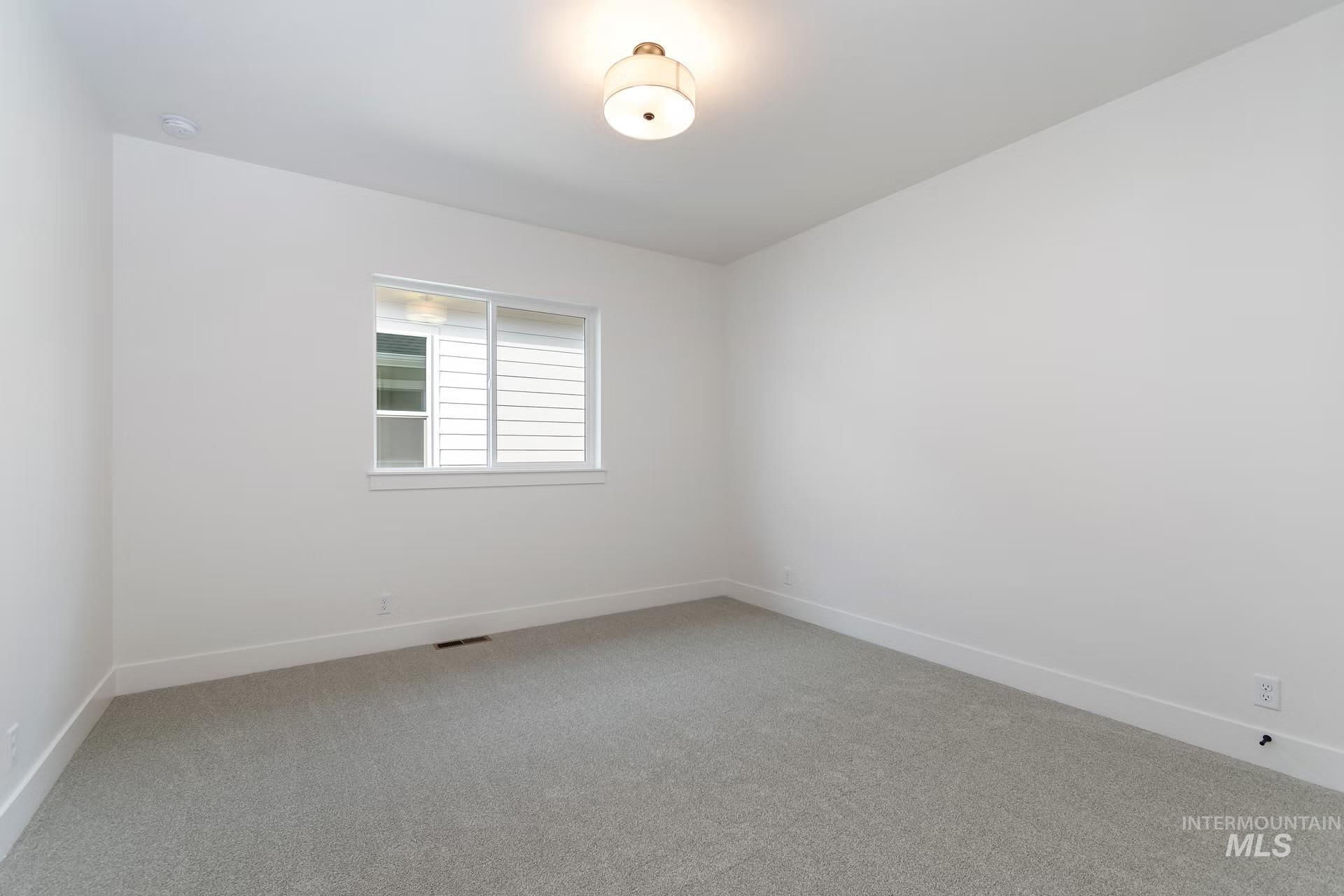 Spare room with light carpet and baseboards