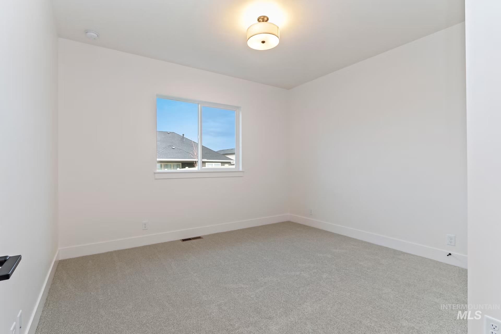 Empty room featuring light colored carpet and baseboards