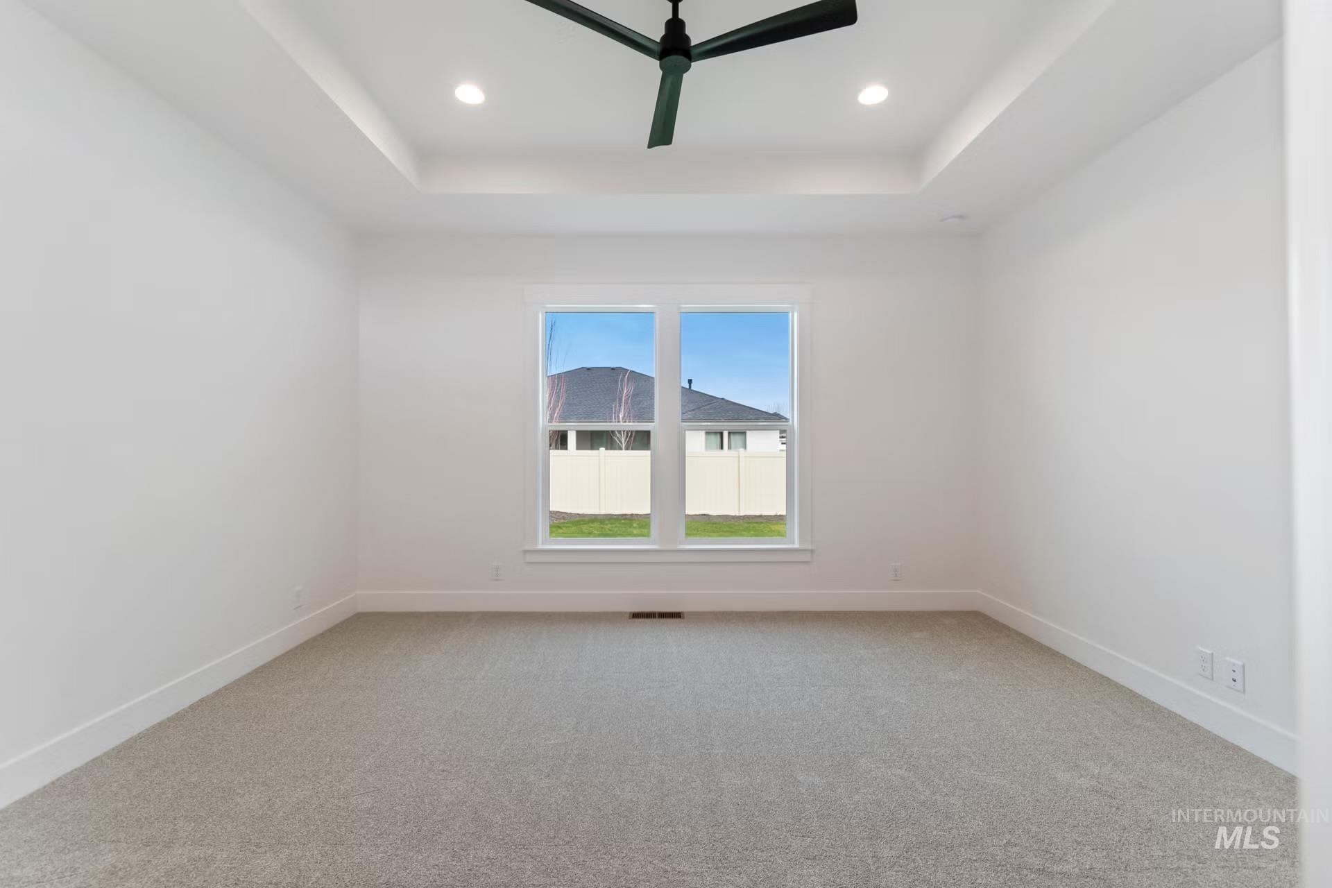 Unfurnished room with a raised ceiling, a ceiling fan, light carpet, and recessed lighting
