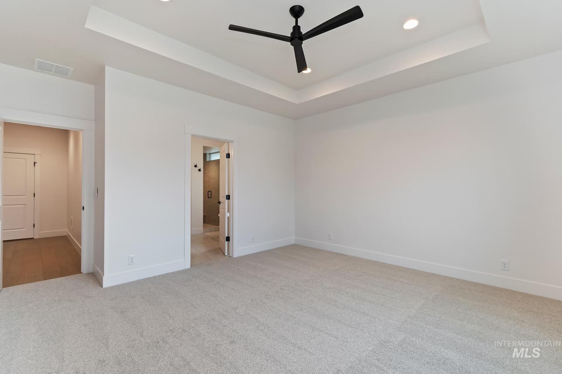 Unfurnished bedroom featuring a tray ceiling, light colored carpet, a ceiling fan, and recessed lighting
