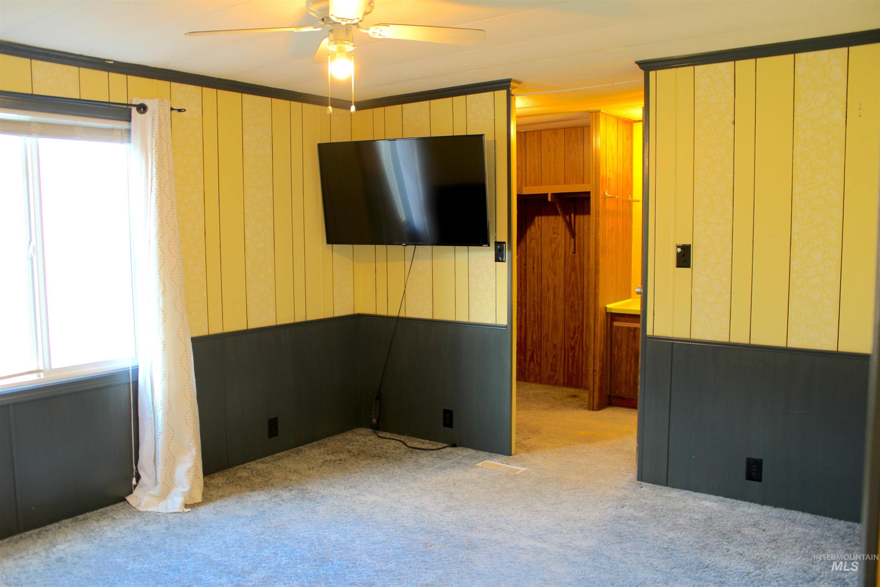Carpeted spare room with wood walls and a ceiling fan
