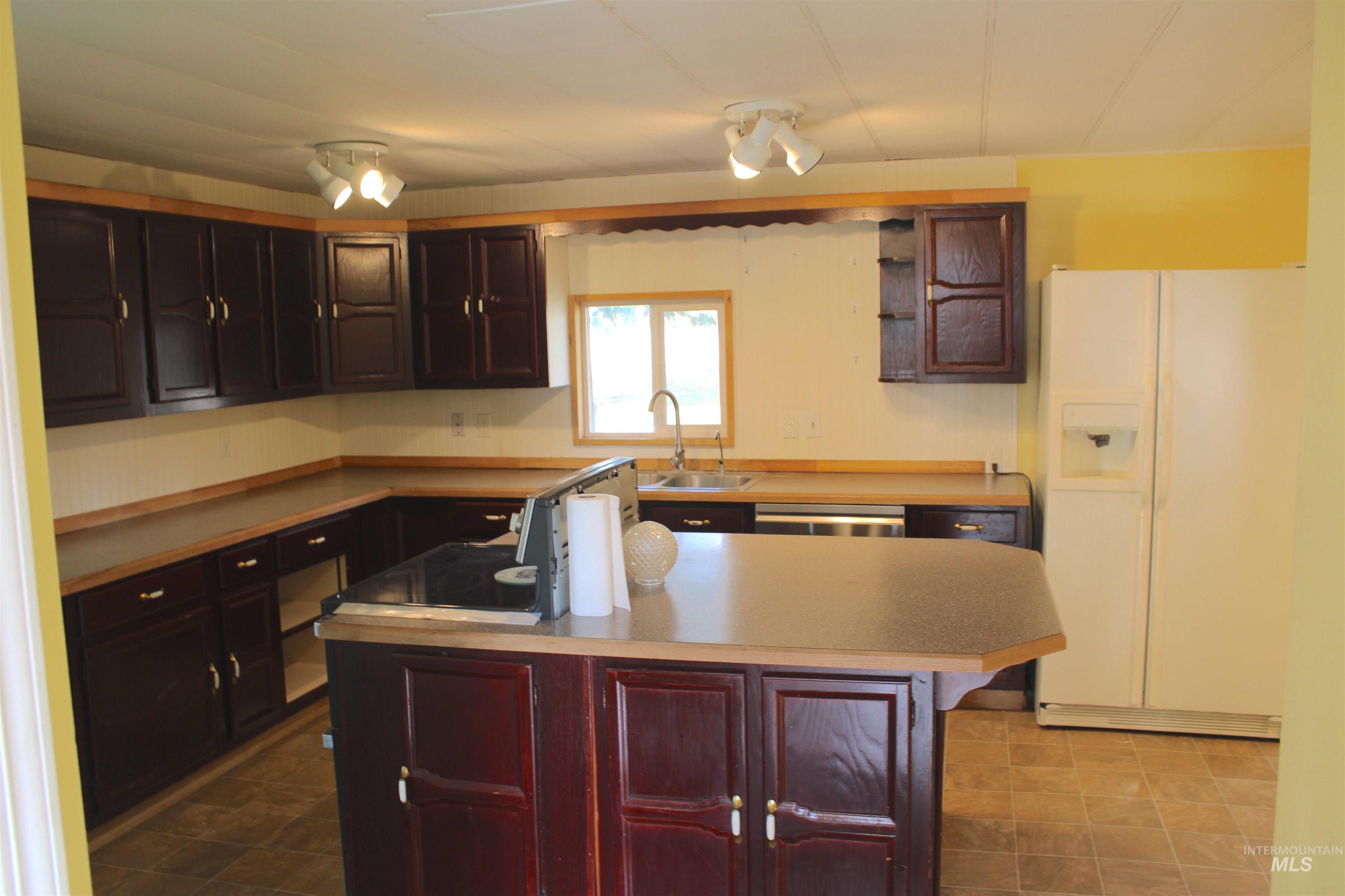 Kitchen featuring white fridge with ice dispenser, a center island, light countertops, and dishwasher